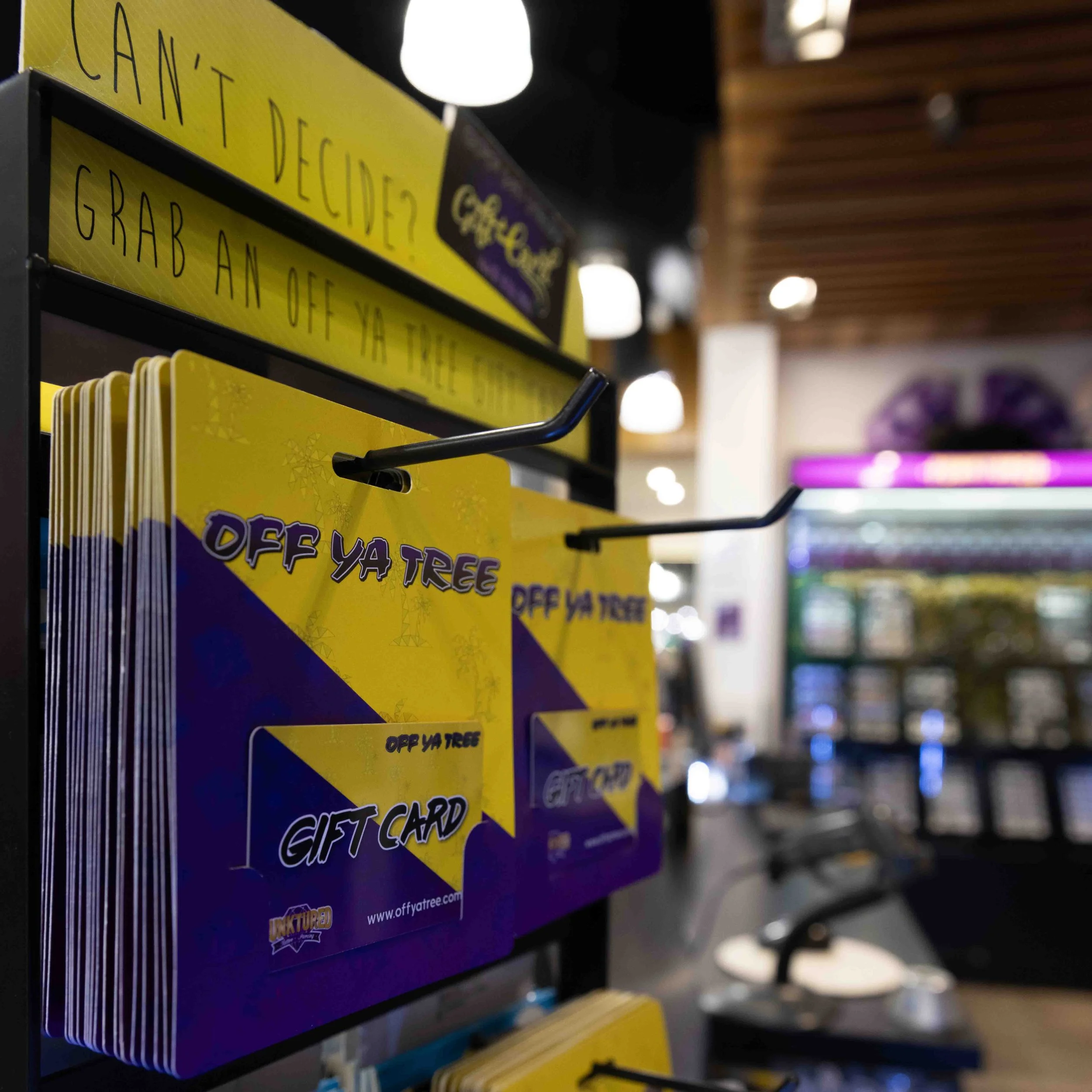 Display of gift cards with yellow and purple design labeled "Off Ya Tree" in retail store.