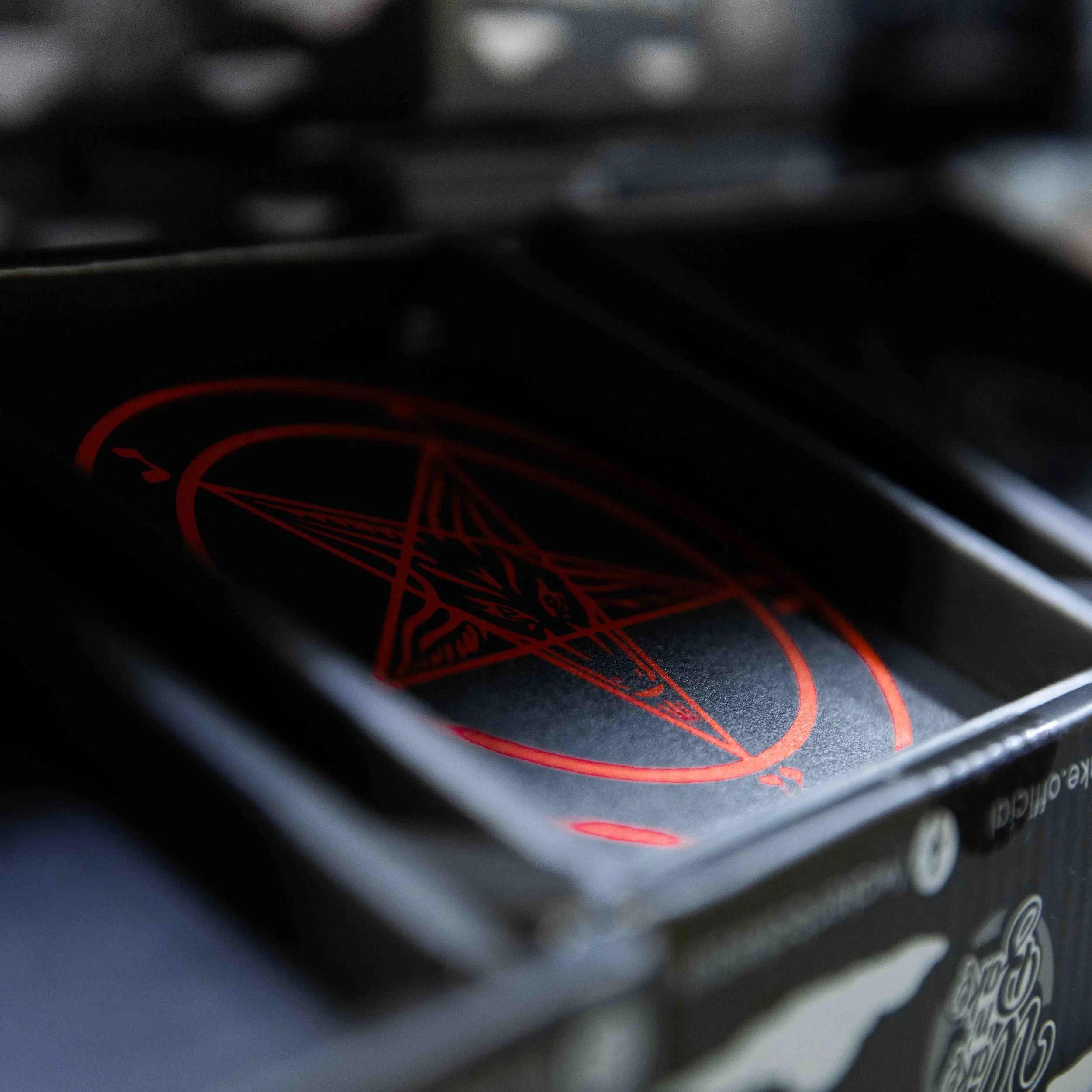 A deck of playing cards with a black and red pentagram design, partially visible in a black box.