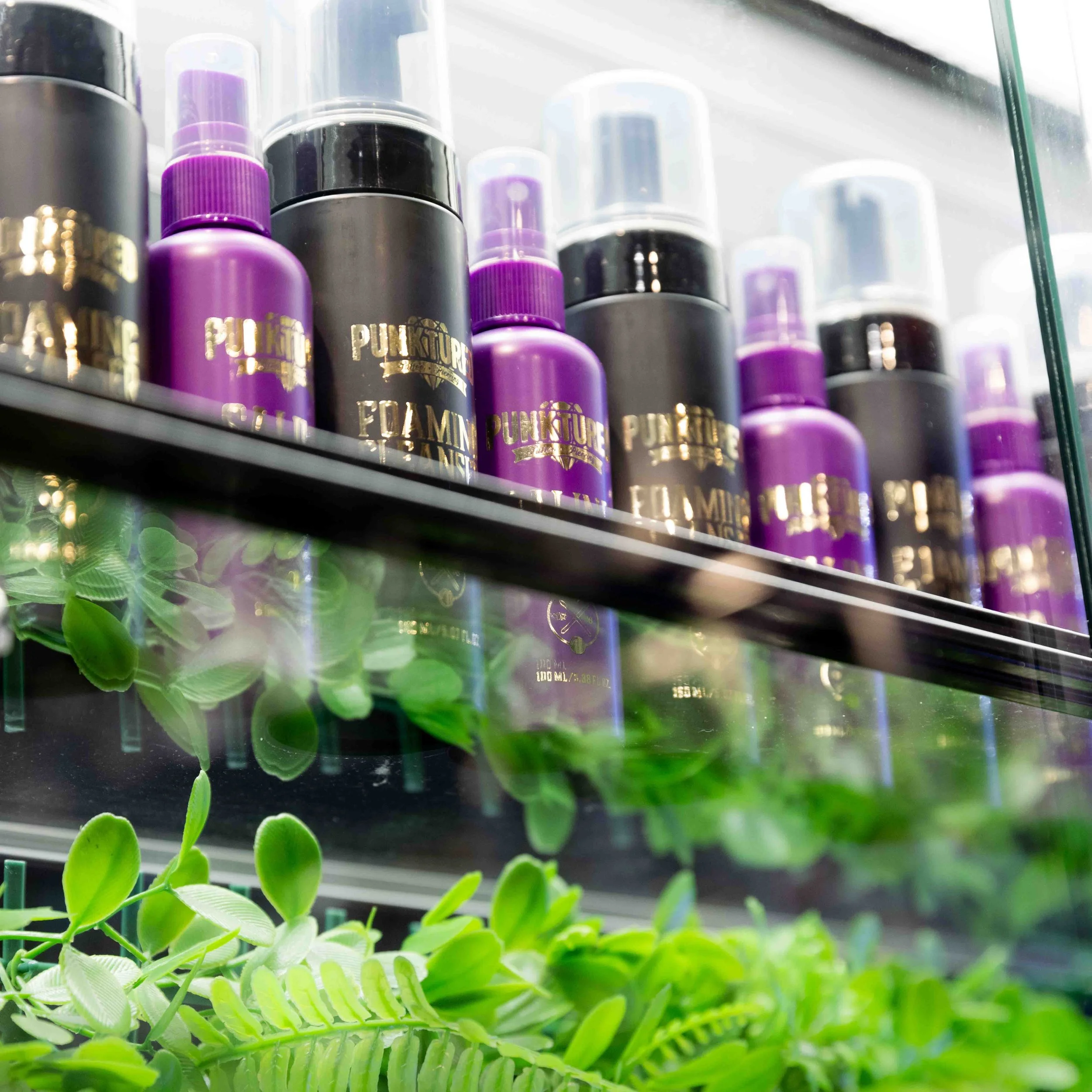 A shelf with purple and black bottles labeled 'Punk Curls' and green plants underneath.