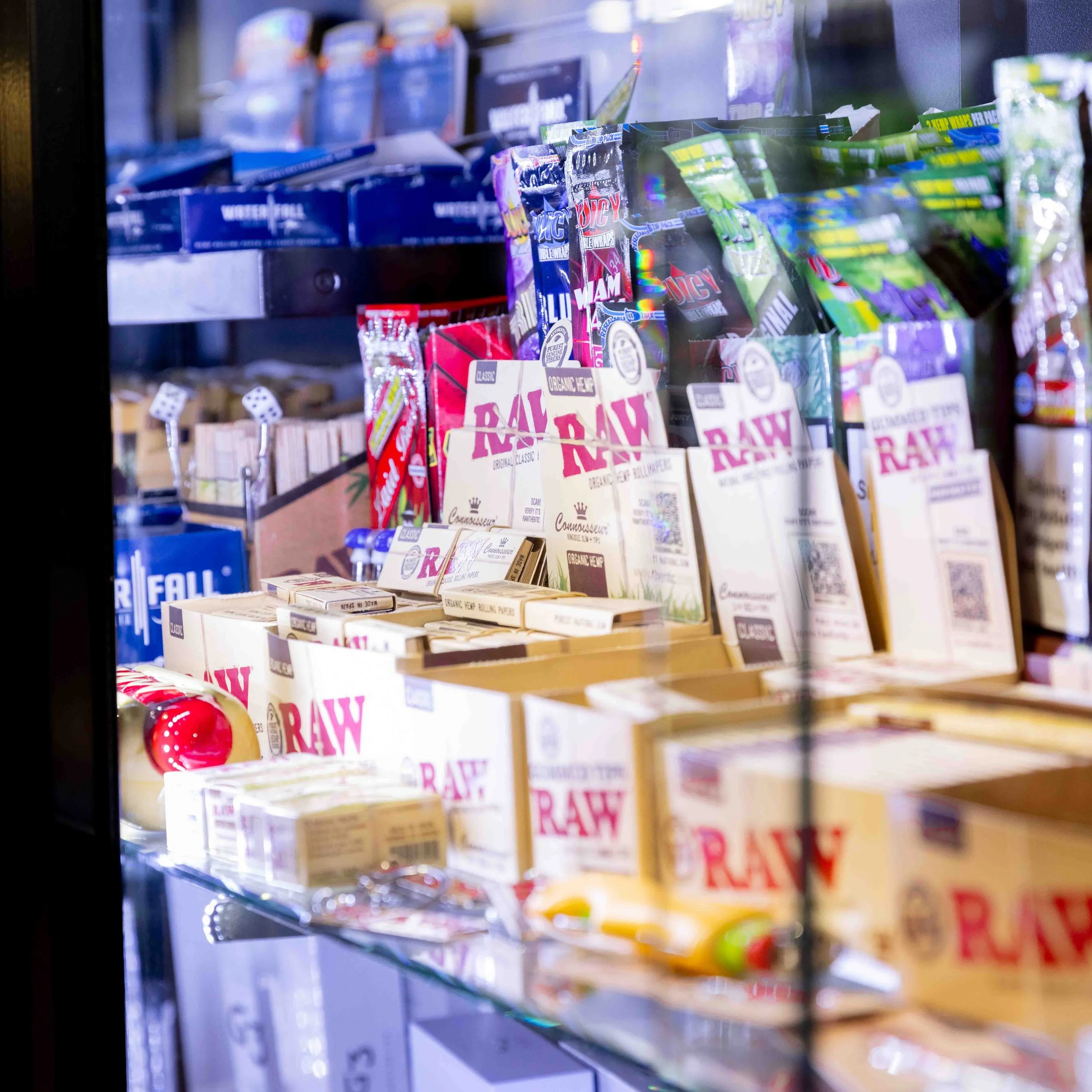A grocery store display with various brands of raw rolling papers and related smoking accessories.