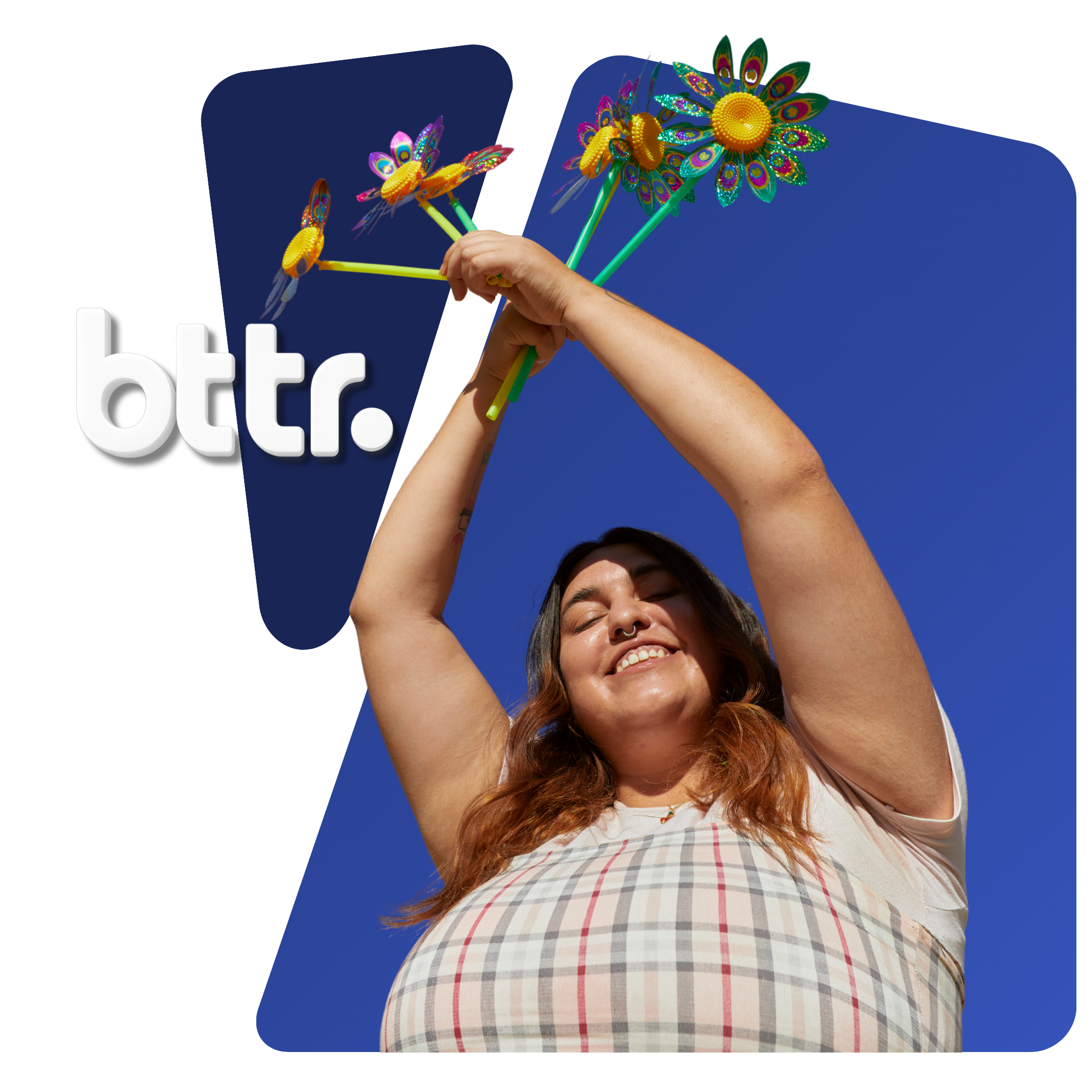 Una mujer pelirroja y con camisa de cuadros sonríe con los ojos cerrados, sosteniendo objetos de colores en forma de flor contra un cielo azul, con el logotipo de "btr." en blanco y negro de fondo.