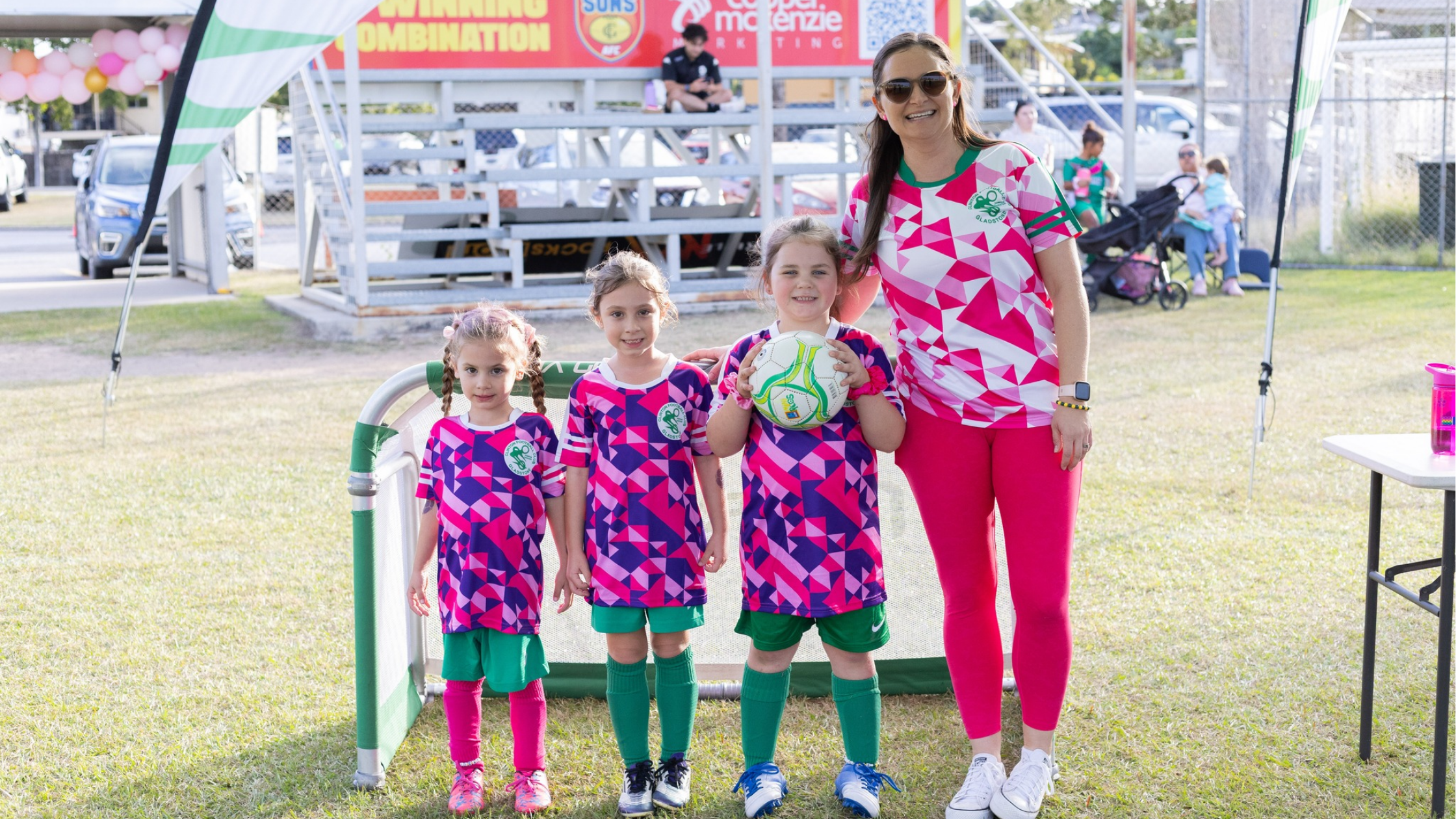 Femal Footballer and junior players in front of soccer goal with ball