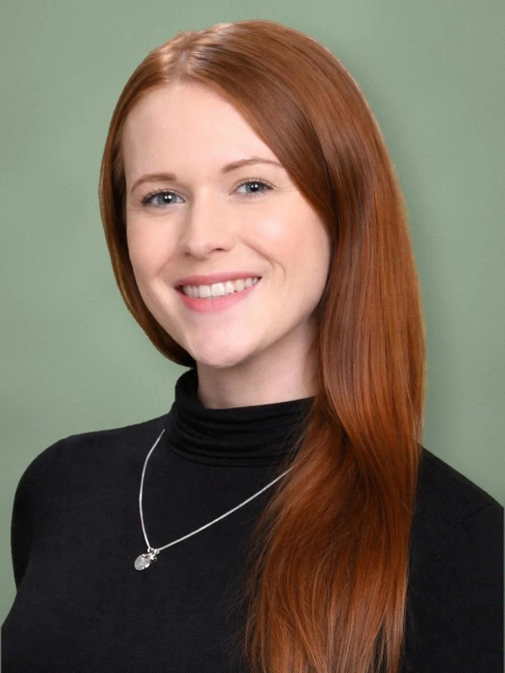 A young woman with long, red hair smiling, wearing a black turtleneck and a silver necklace, against a green background.