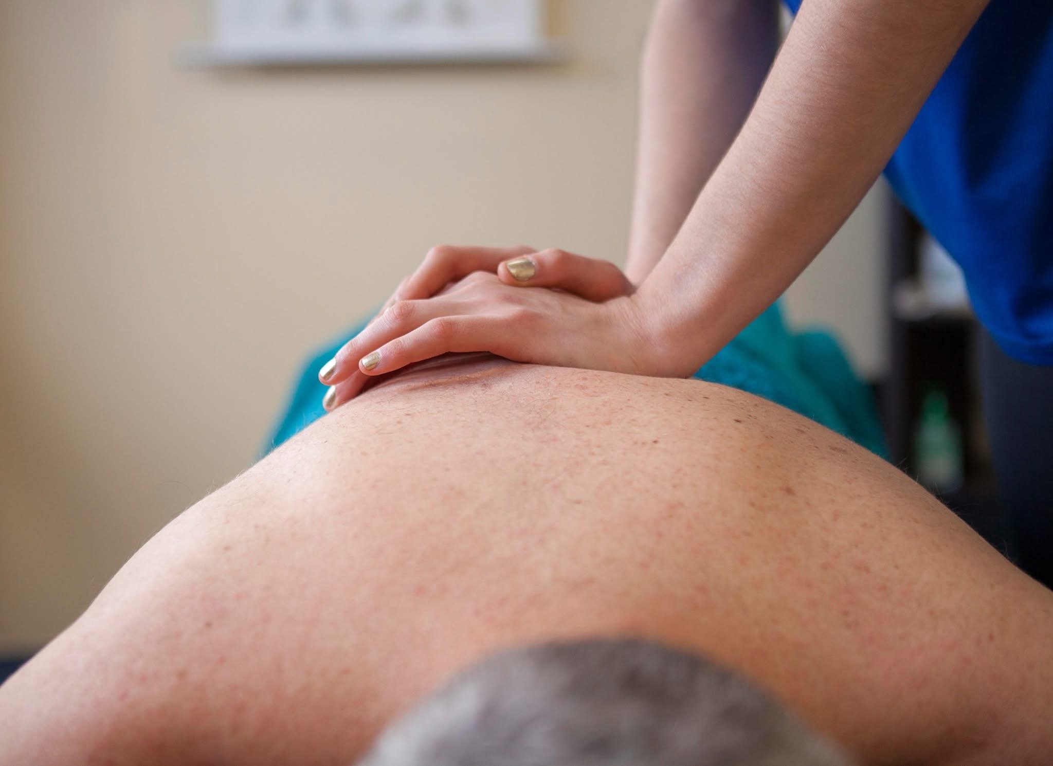 Close-up of a person receiving a massage, focusing on their arm and back with hands gently pressing on their shoulder.