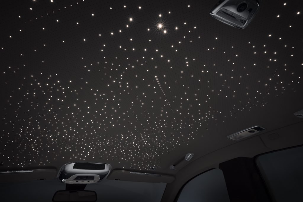 The interior ceiling of a car with a starry night sky-styled star projection lights.