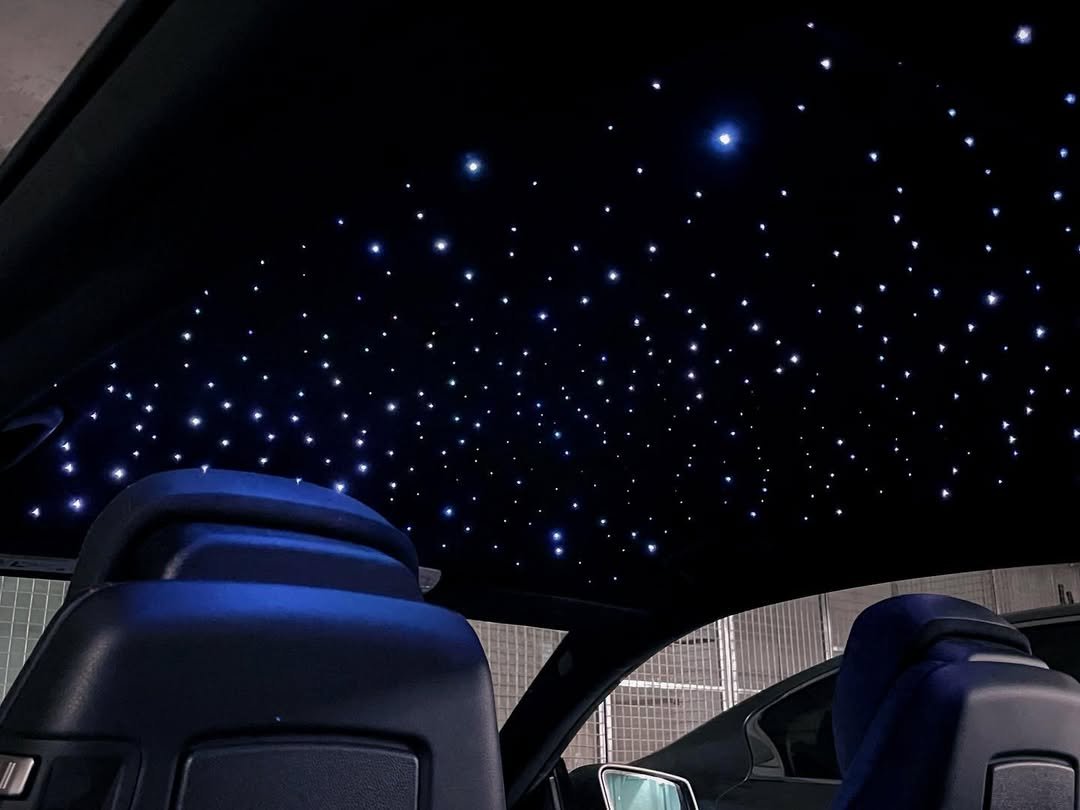 Car interior with a ceiling that has star-like LED lights creating a starry sky effect.