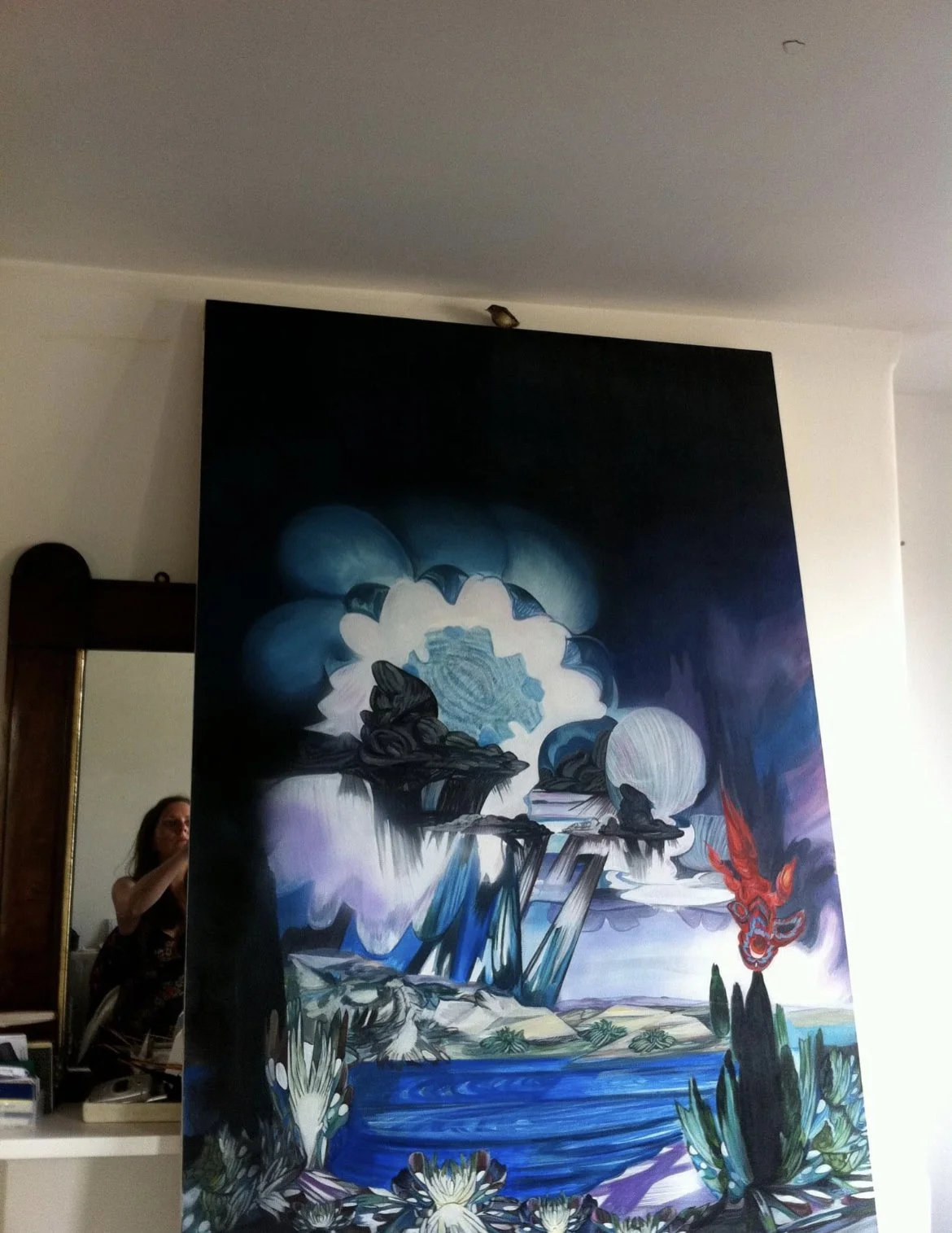 Large, colorful abstract painting on a wall with a woman partially visible in the background.