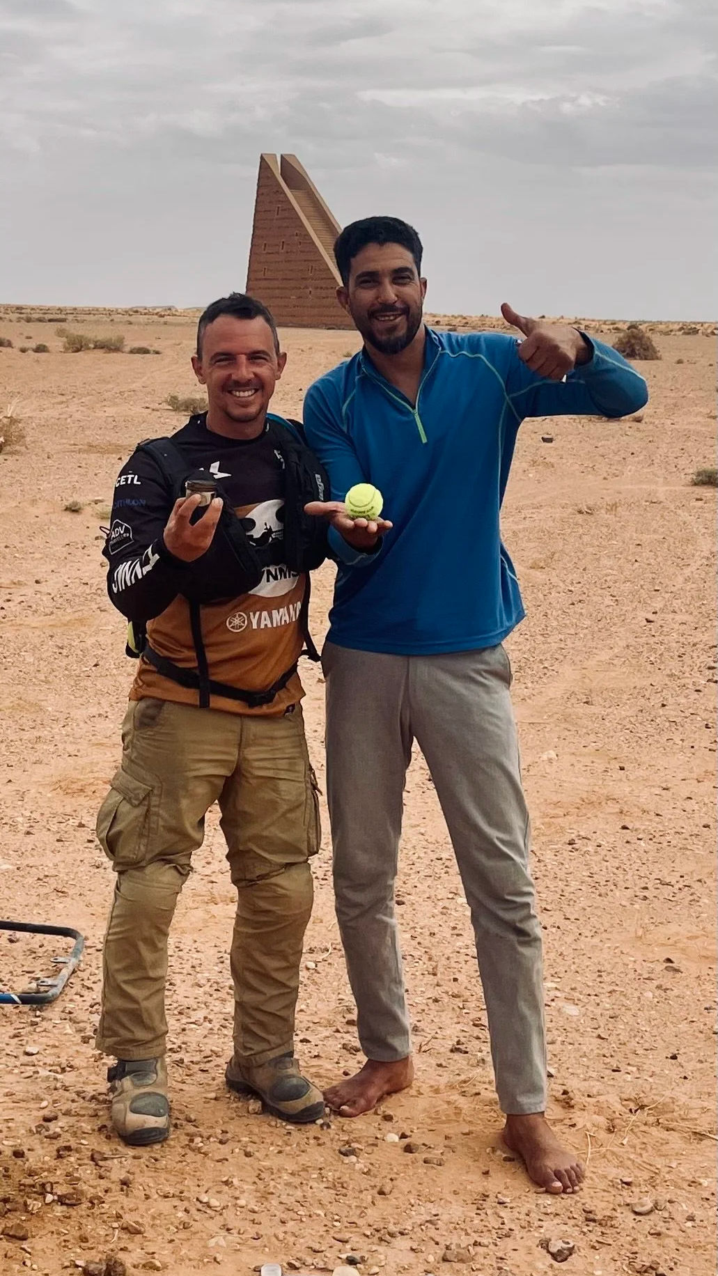 João Beltrão founder of Beyond T7nnis holding a piston and a Moroccan men holding a tennis ball with l'escalier celeste in the background