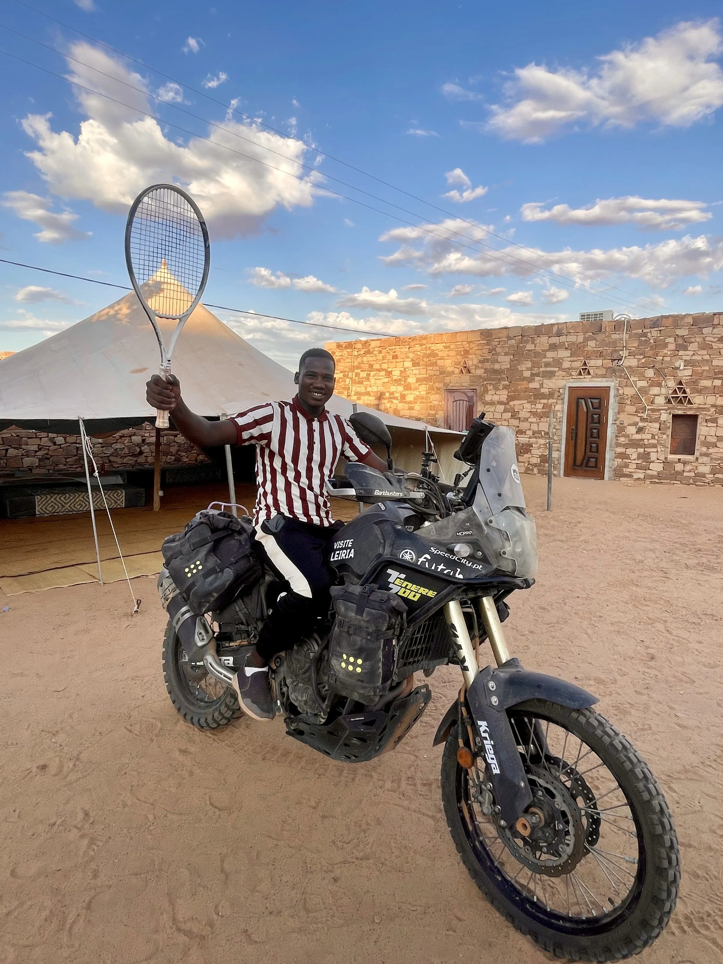 Man on a  Yamaha Ténére 700 motorcycle holding a tennis racket during a Beyond T7nnis mission

