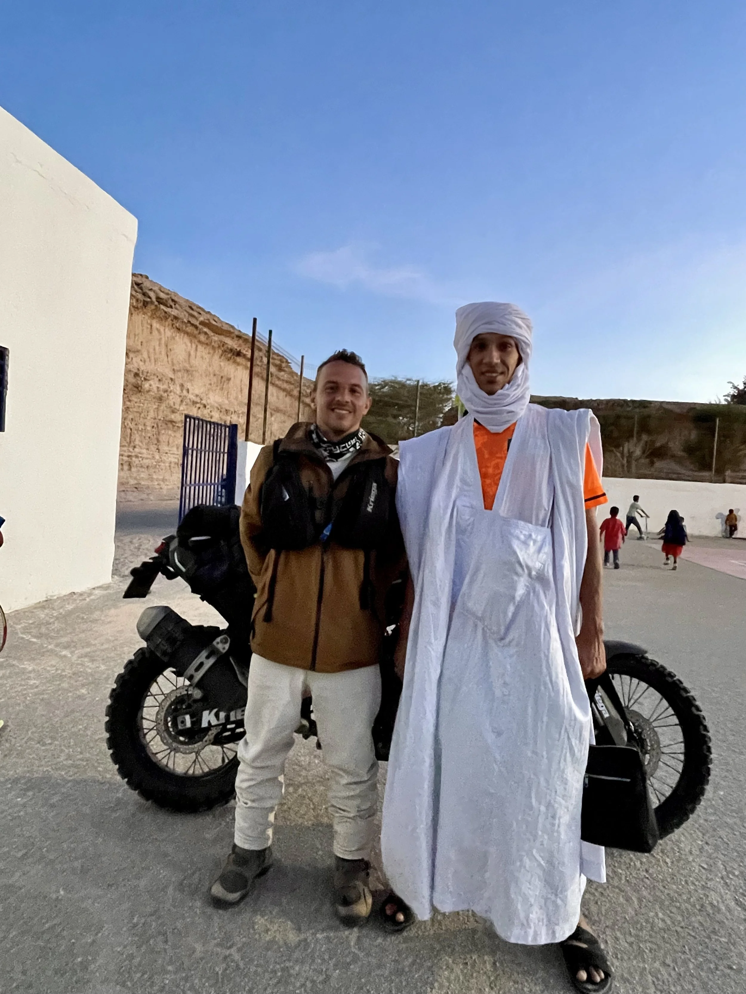 João Beltrão founder of Beyond T7nnis with his Yamaha Ténére 700 motorcycle at the SNIM tennis club in Mauritania with the coach

