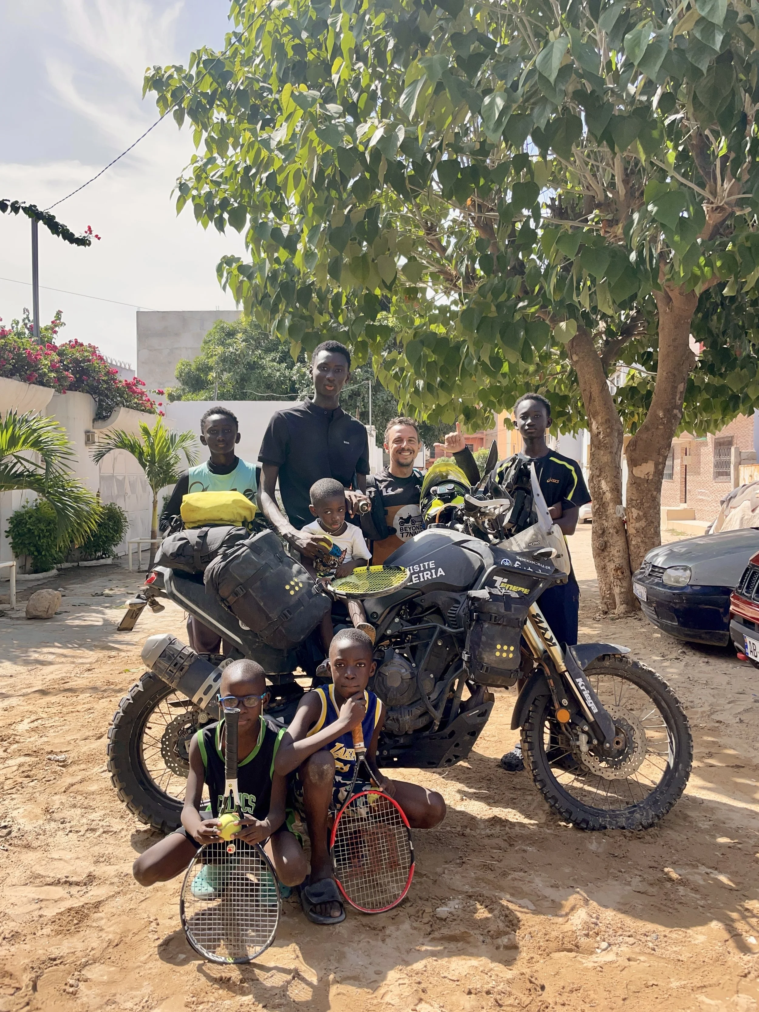 João Beltrão founder of Beyond T7nnis with his Yamaha Ténére 700 motorcycle and a group of young tennis players during a Beyond T7nnis mission in Dakar, Senegal
