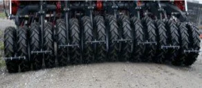 Close-up of multiple large tires arranged in a row on a gravel surface.
