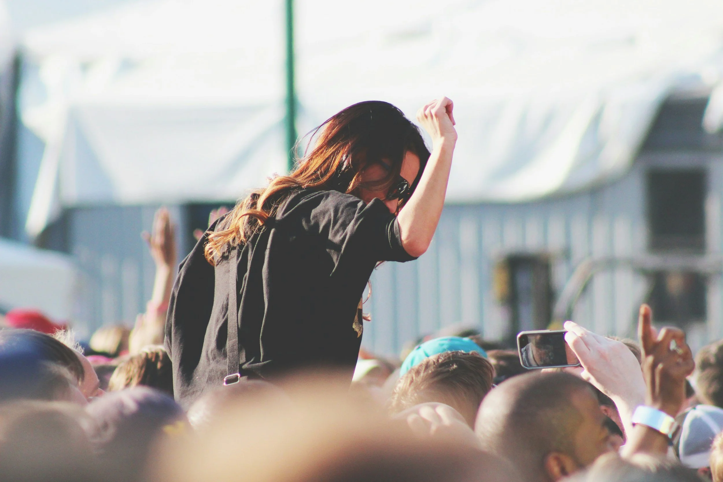 A woman at an outdoor event. She is surrounded by a crowd, some people holding up phones powered by solar phone charging stations