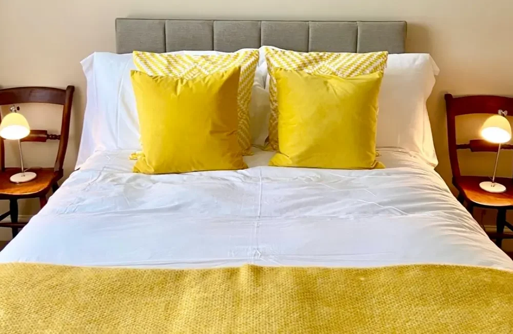 Double bed with yellow bedding and cushions