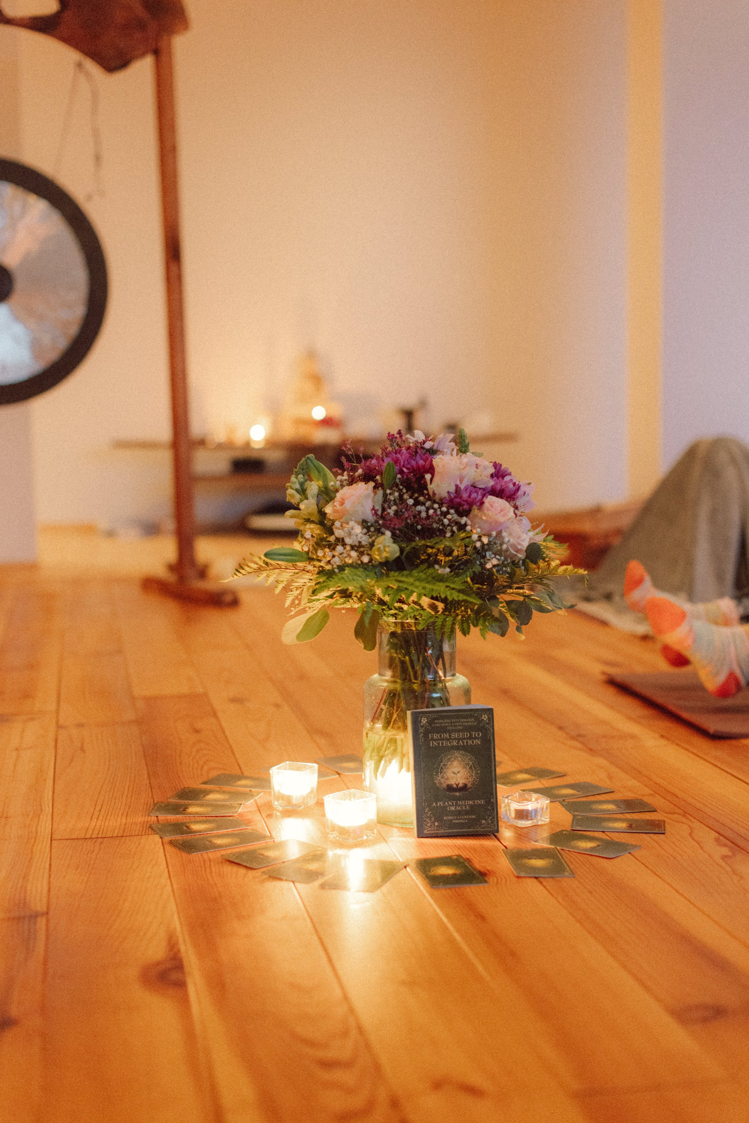 Three tarot cards on a wooden table with candles, driftwood sculptures, and decorative objects in the background.