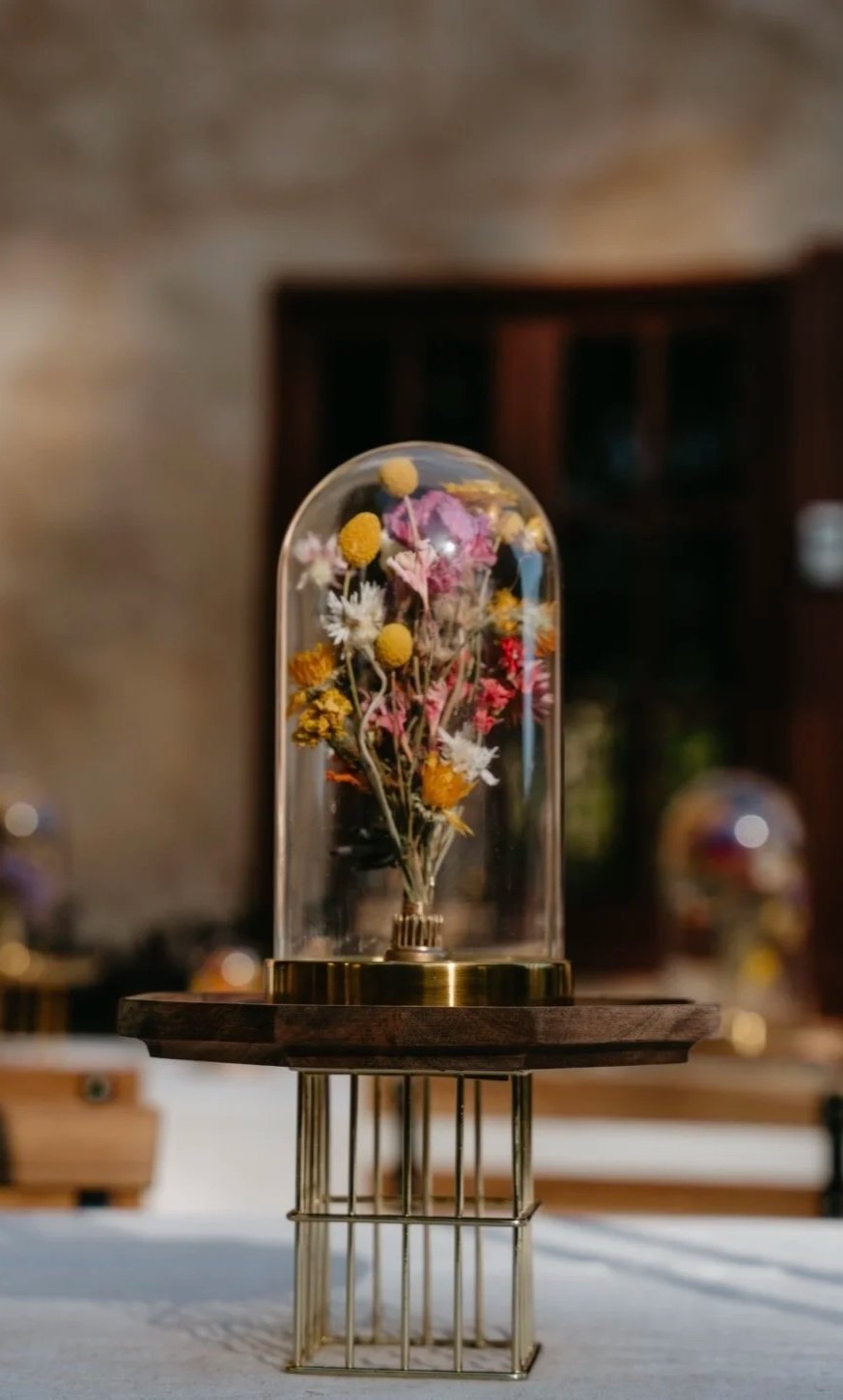 A bell jar or cloche made of glass and brass with a dried flower bouquet by fable and twig at an elopement or wedding