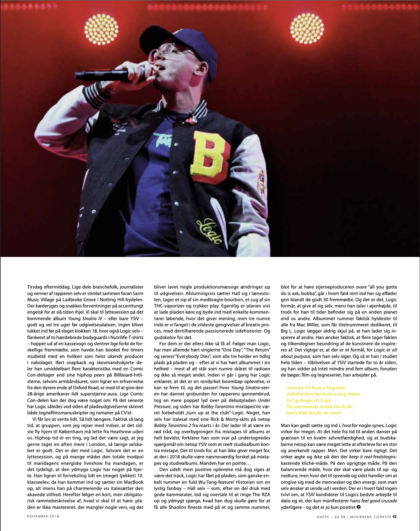 A male performer singing into a microphone on stage, wearing glasses, a black baseball cap, and a varsity jacket with a yellow and red 'B' patch, against a stage background with red lighting. Logic, Gaffa, London