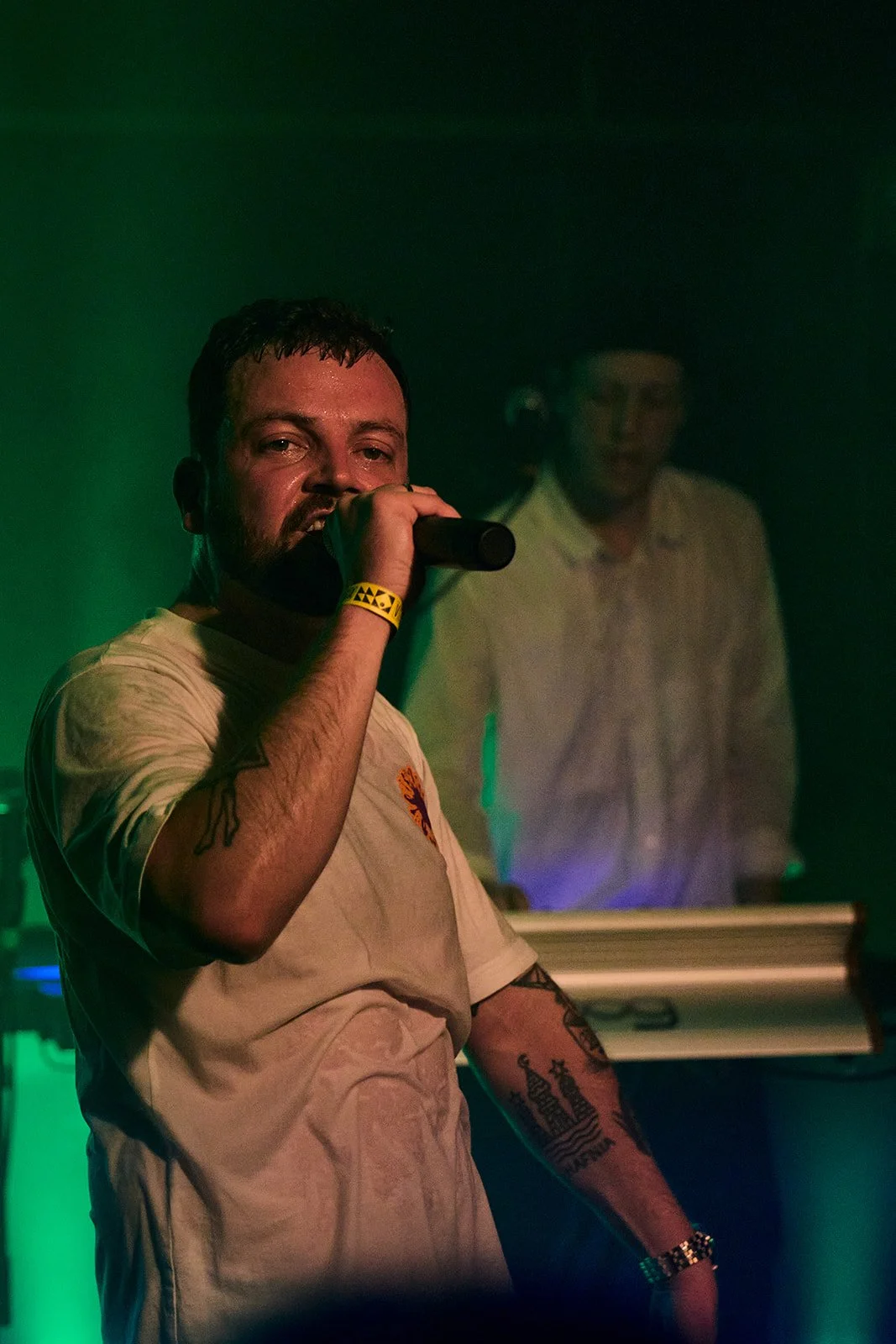 A man singing into a microphone with a keyboard in the background, green and purple lighting. Ideal Bar, Vega, Frit Løb, Cillian Mxrphy