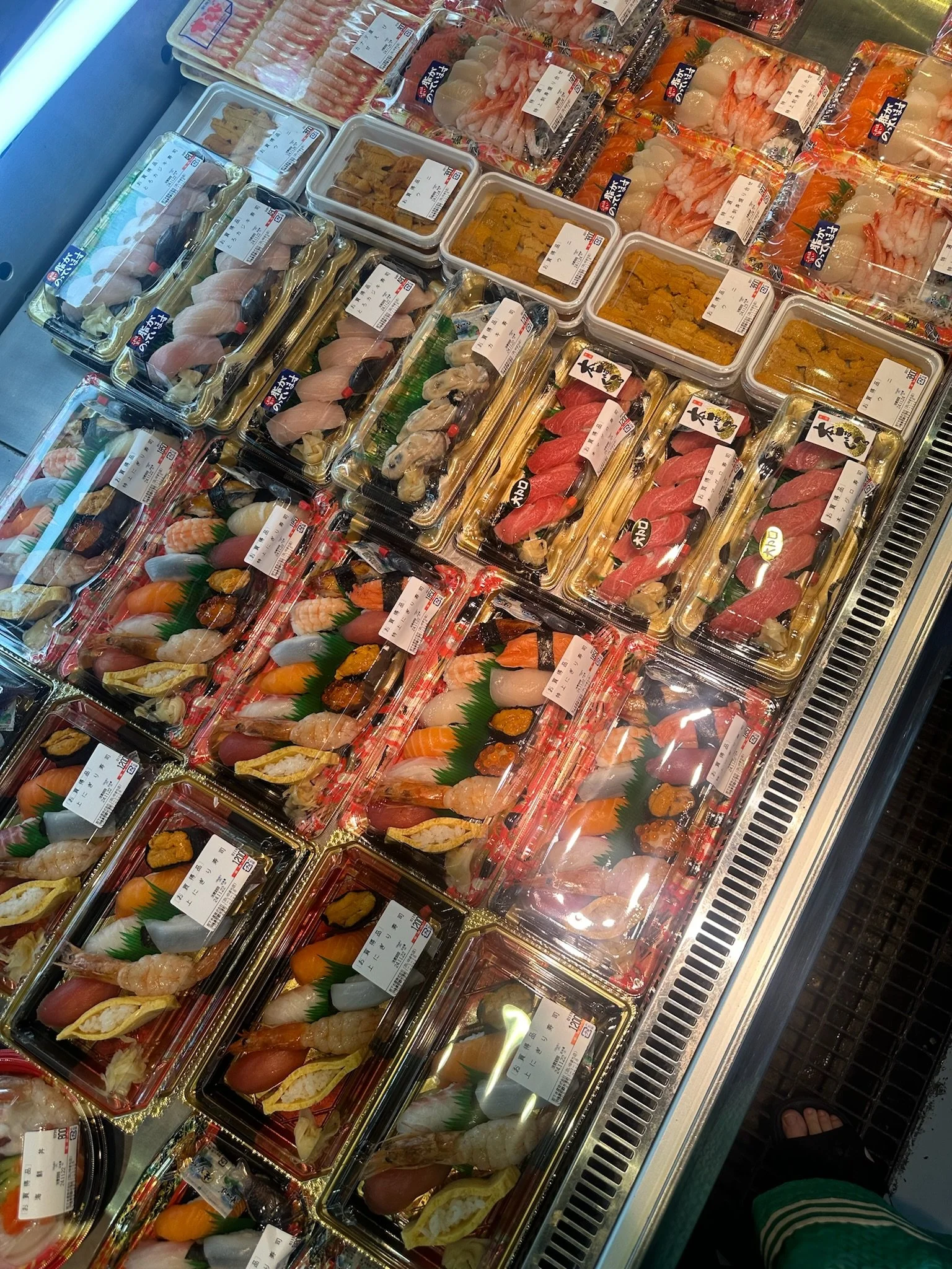 Assorted sushi and sashimi in plastic containers at a grocery store display in Naha, Okinawa, Japan