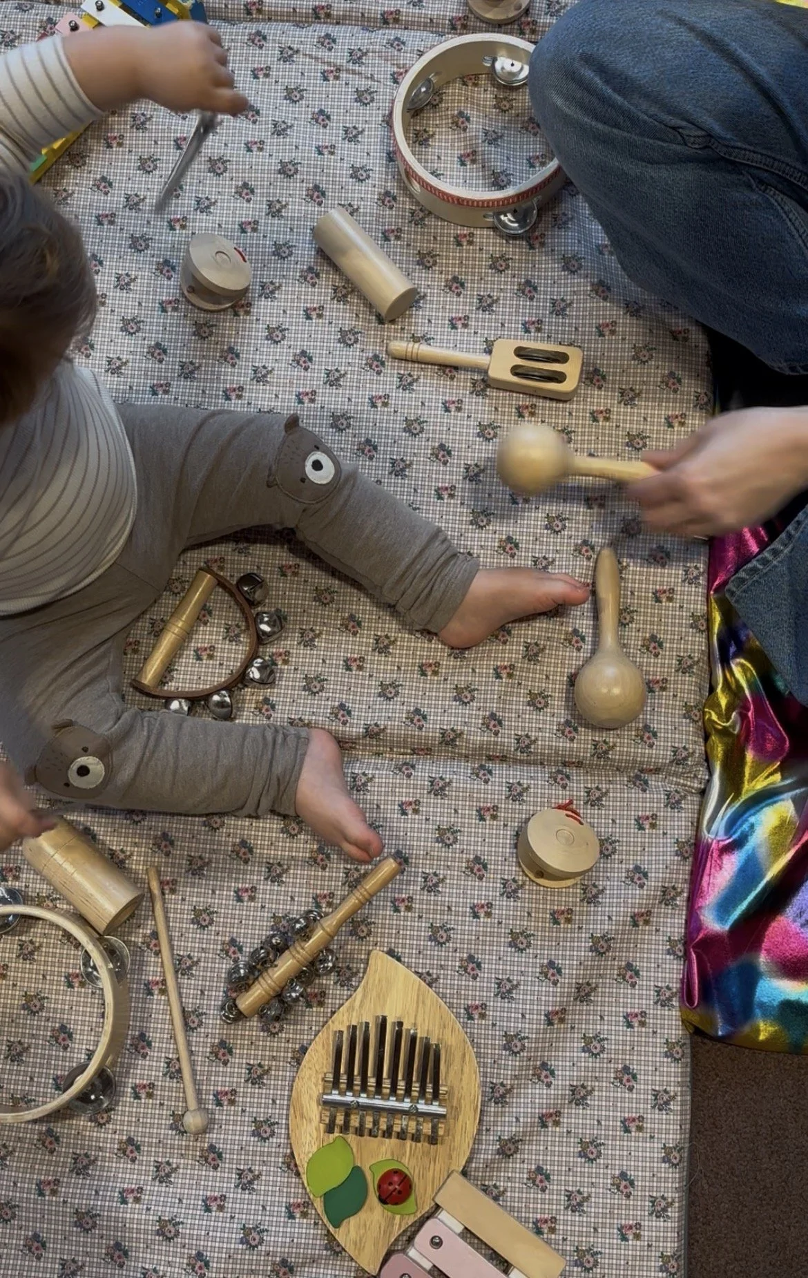 Enfants jouant avec des instruments de musique en bois sur une nappe à motifs floraux.