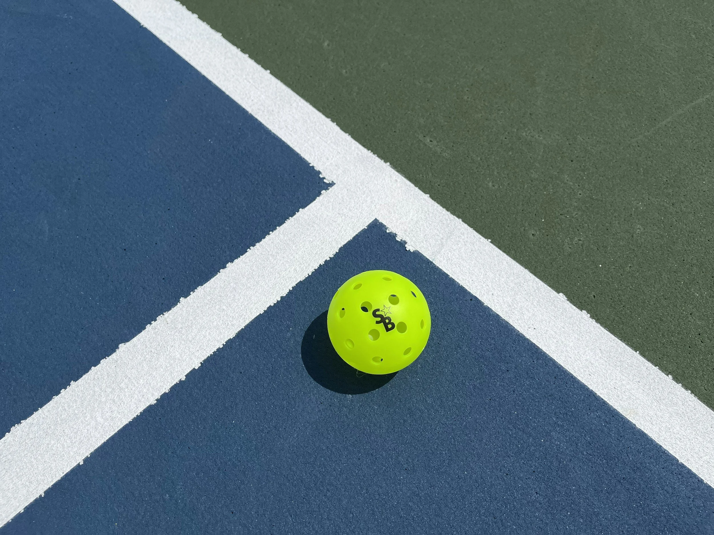 Close-up of a sports field with a white line marking on green grass.