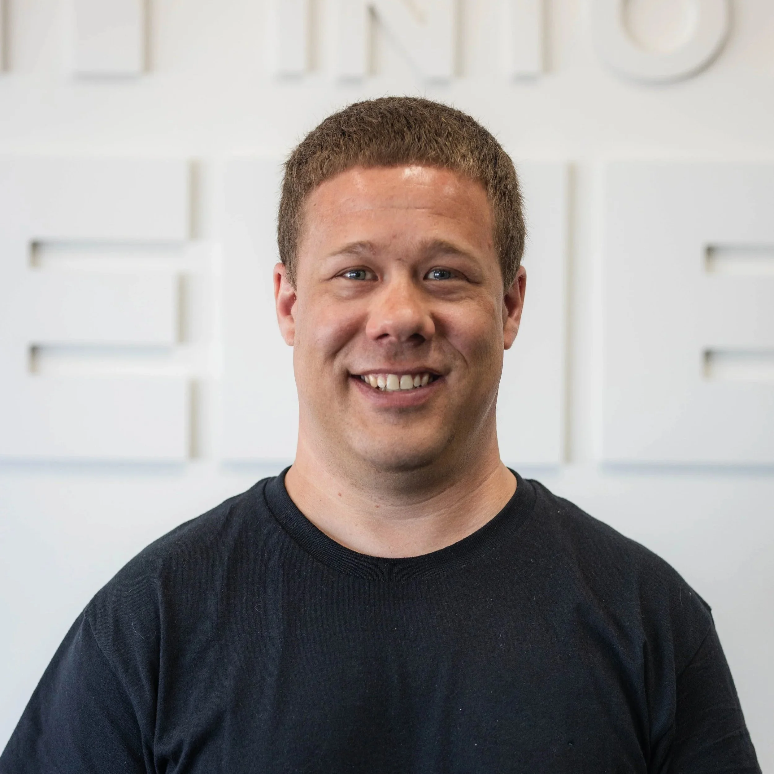 Man with a buzz cut wearing a black shirt