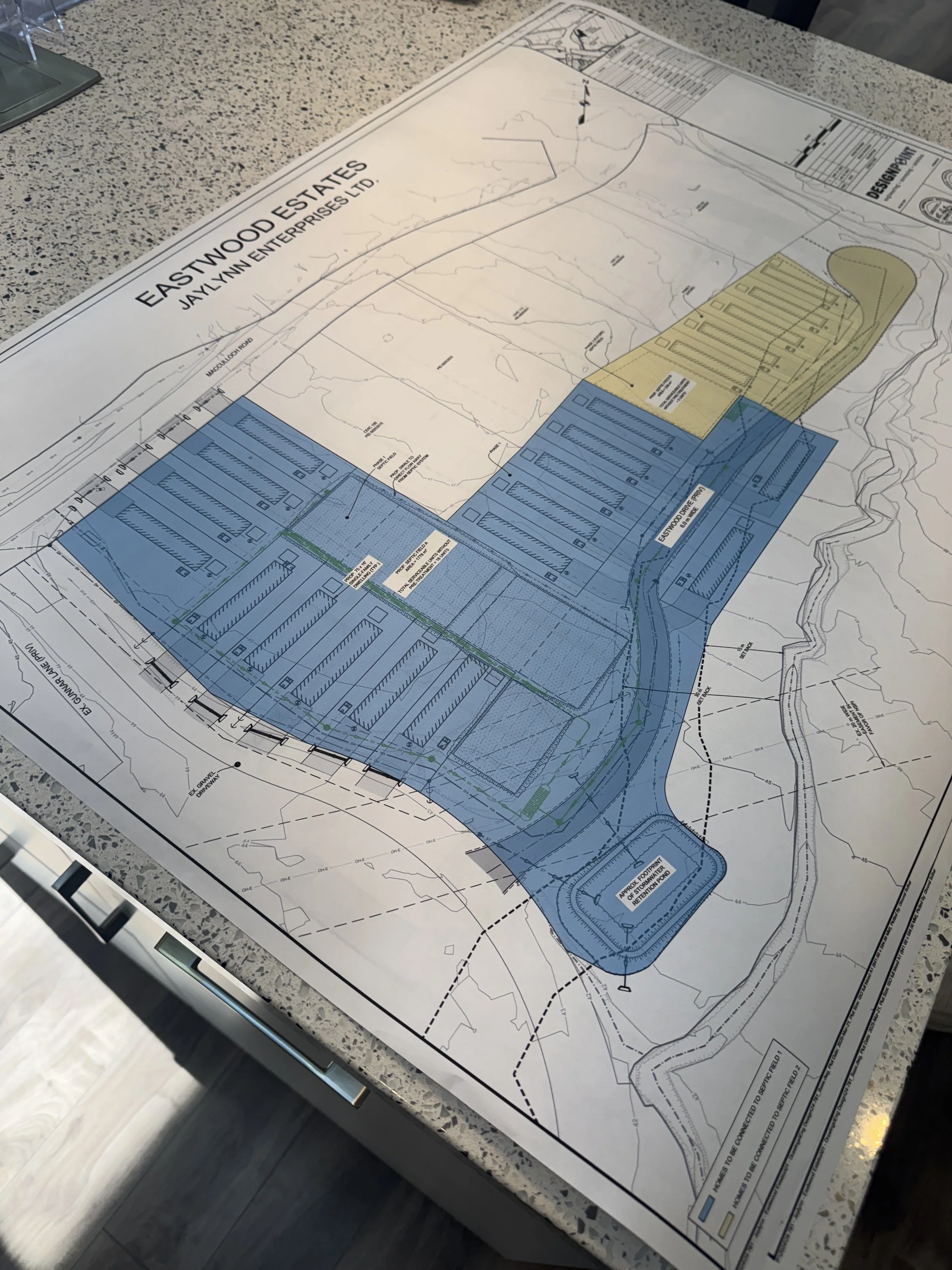 Site plan for Eastwood Estates by Jaylyn Enterprises Ltd., showing layout of parking lots, roads, and land boundaries with colored sections on a large blueprint.