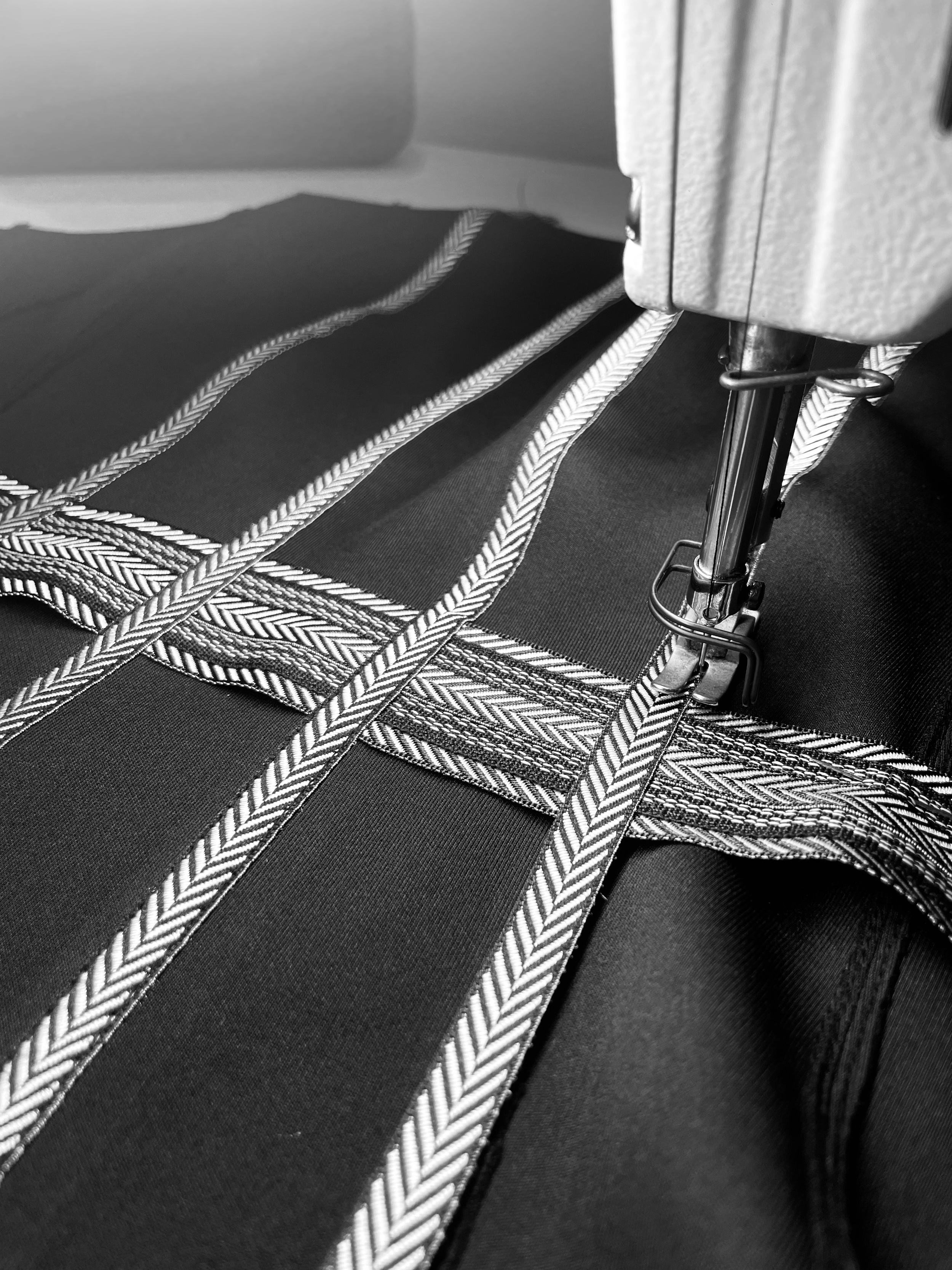 Close-up of a car seat with seatbelt and metal latch, focusing on the black fabric with white striped pattern.