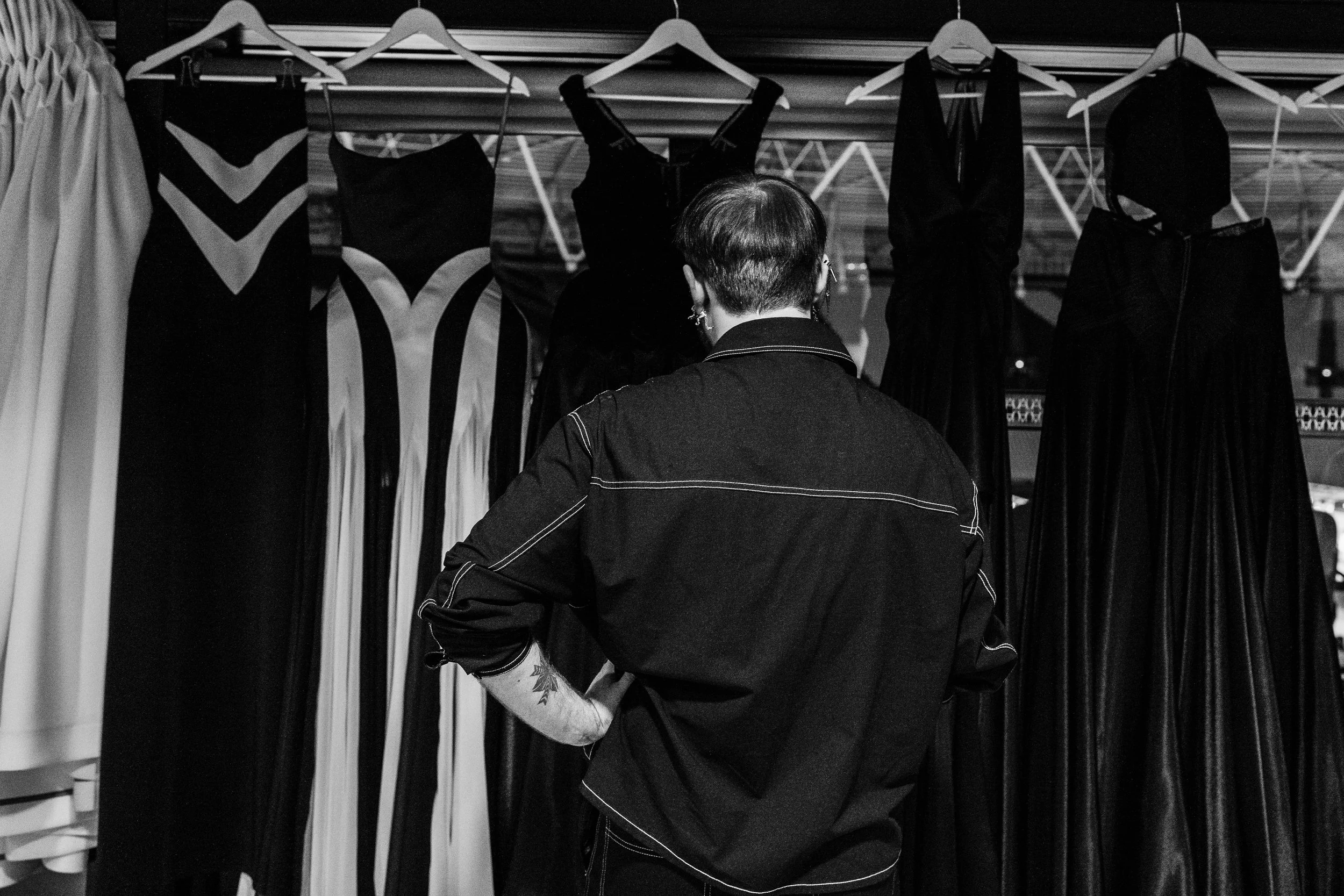 Person browsing dresses on a clothing rack in a store.