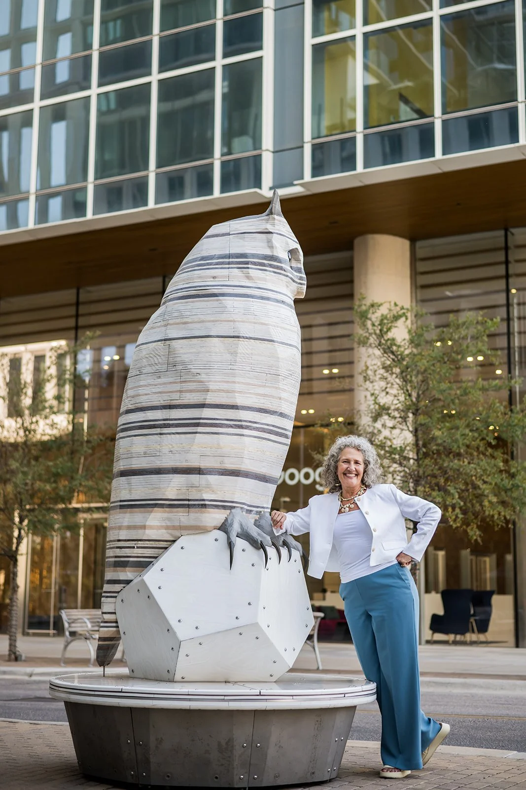 Photo of a woman standing next to large statue of an owl in downtown Austin, Texas,, inviting executive coaching clients.