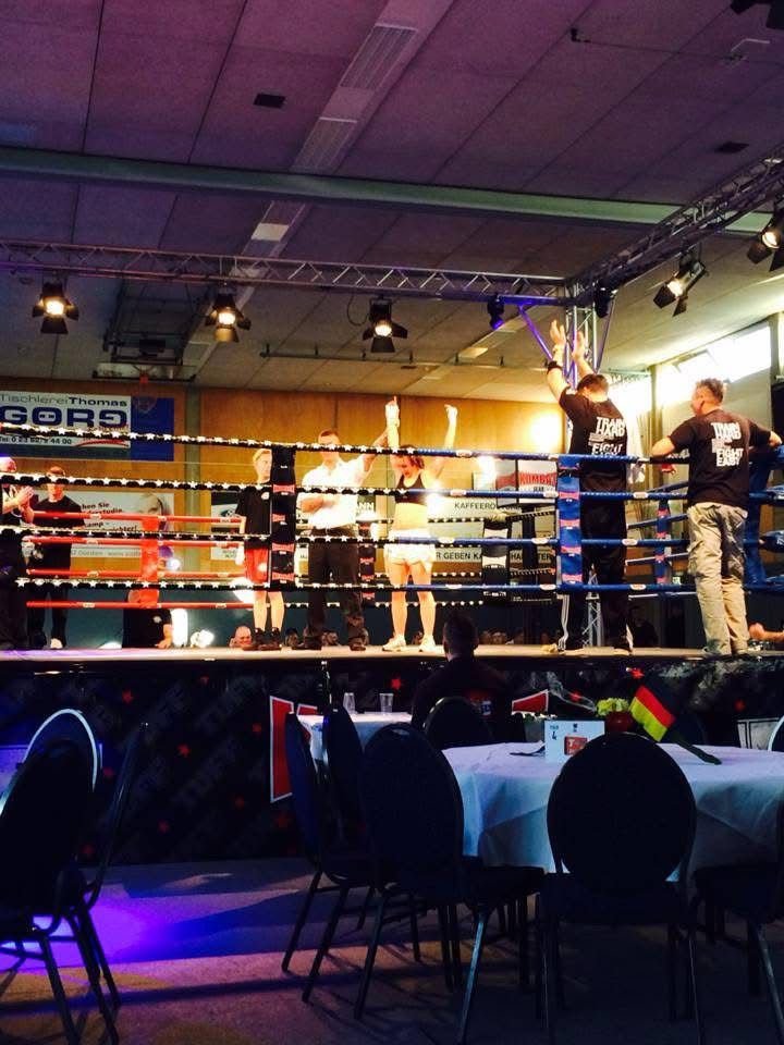 Boxkampf in einer Kampfarena mit ring, Kämpfer, Schiedsrichter und Publikum im Hintergrund, bei einer Veranstaltung im Saal.