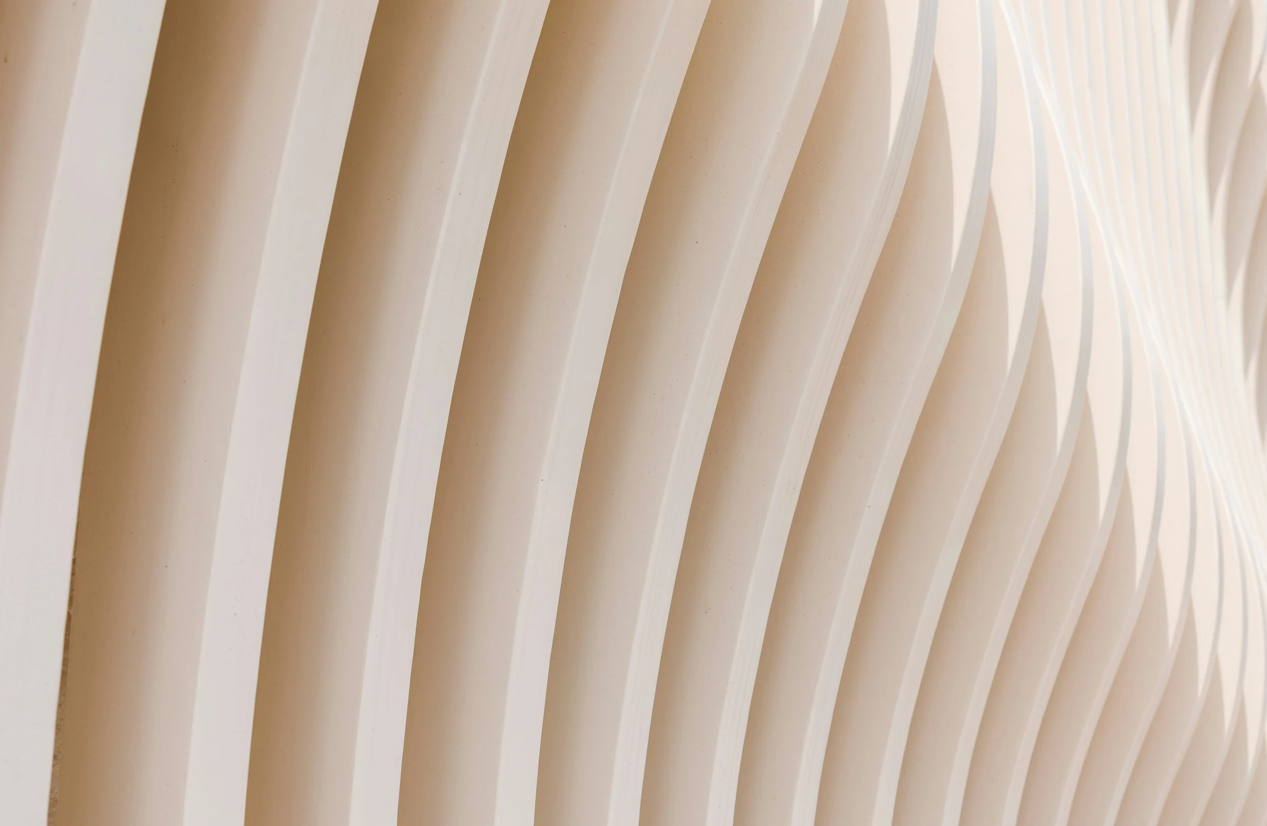 Close-up of a series of cream-colored vertical slats or fins creating a modern architectural design.