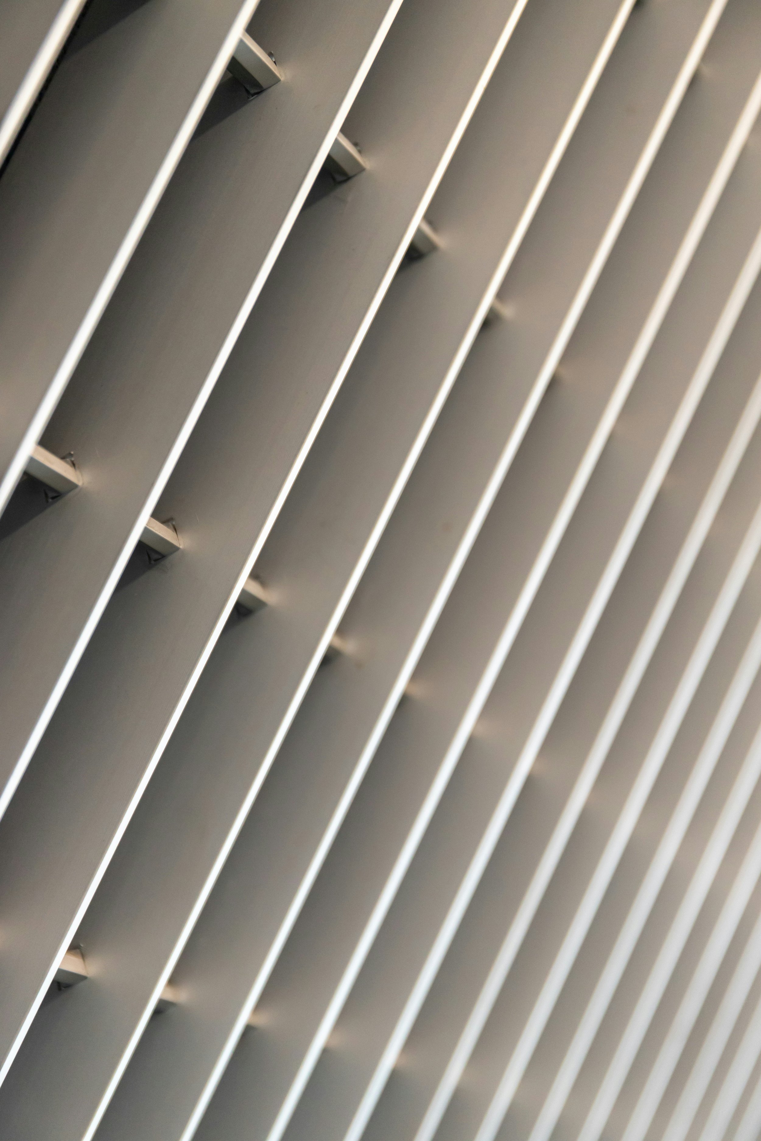 Close-up of a modern, metallic ceiling with evenly spaced, parallel white beams or panels.