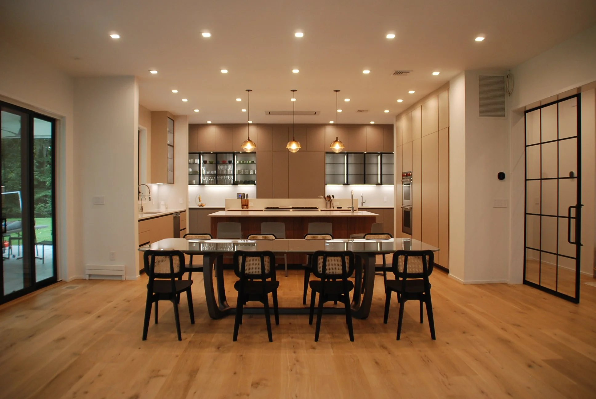 Modern kitchen with recessed ceiling lights, under-cabinet strip lighting, and pendant lights over an island, showing layered ambient and task lighting design. OVERTHINK