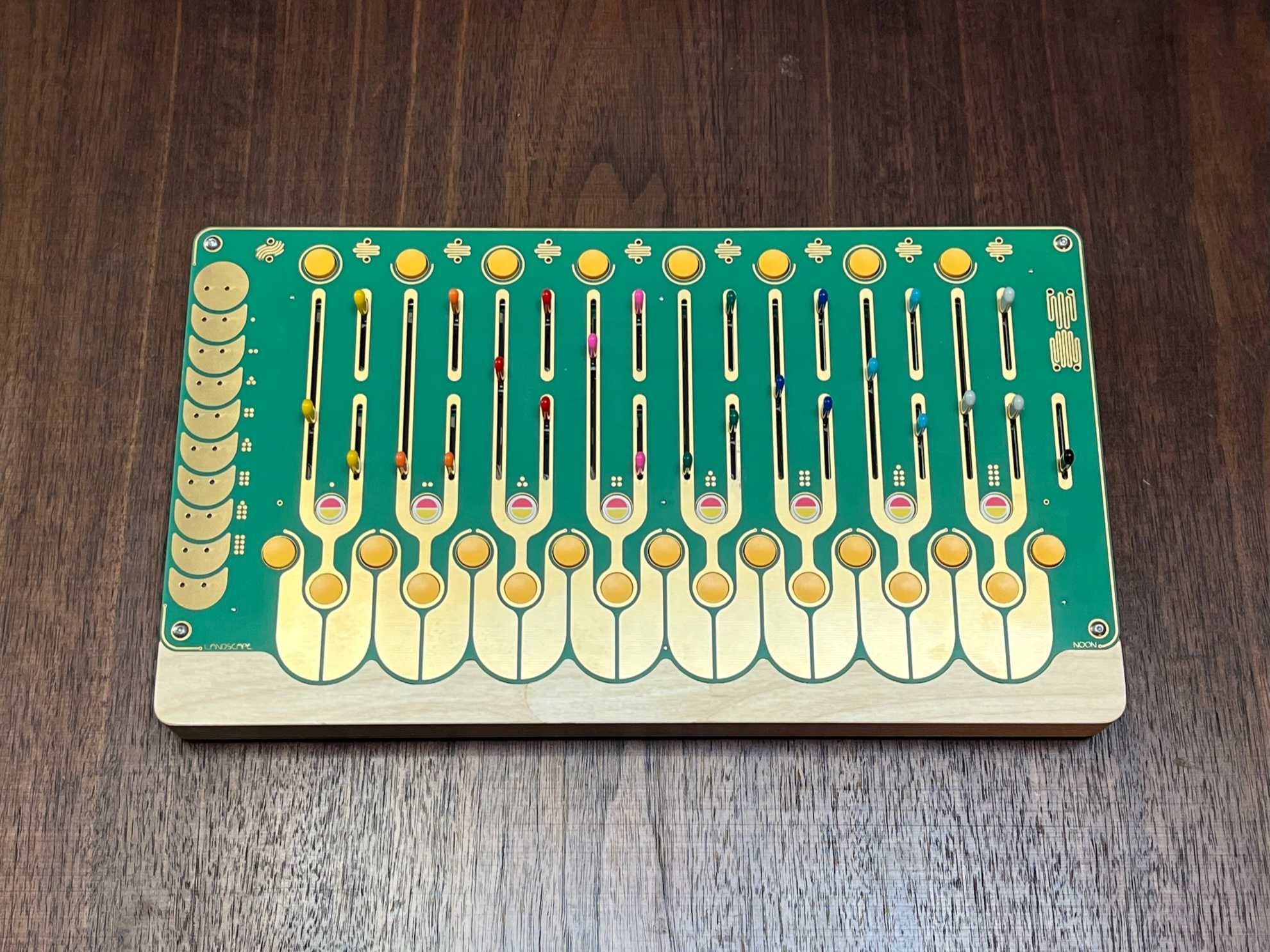 Birch plywood and PCB rectangular instrument with 8 sets of three vertical sliders and 4 push buttons.  CV/Gate jacks along the left side, individual outputs along the top edge and two summed outputs along the left side.