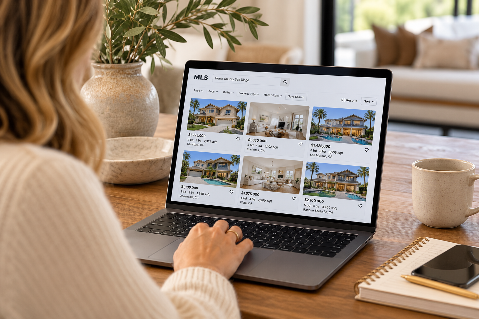 Prospective homebuyer browsing North County San Diego real estate listings on a laptop, comparing property photos of homes in Carlsbad, Encinitas, Oceanside, and surrounding communities.