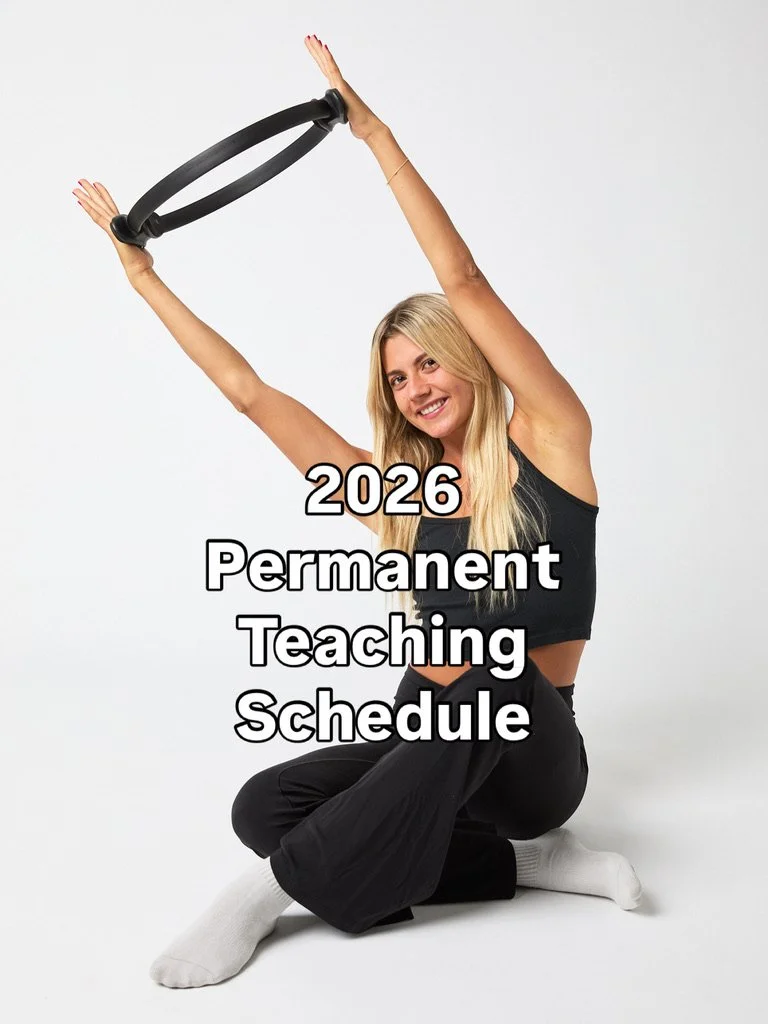 A smiling young woman with long blonde hair, wearing a black tank top and black pants, sitting cross-legged on the floor holding a Pilates ring above her head, against a plain white background. Overlaid text reads '2026 Permanent Teaching Schedule'.