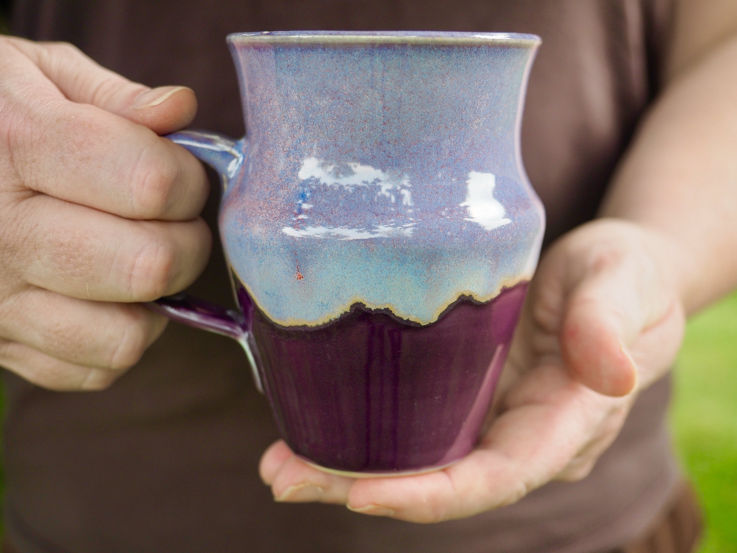 Person holding a colorful ceramic mug with a purple glaze combination. Copyright Kate O'Rourke/Maritime Ceramics.