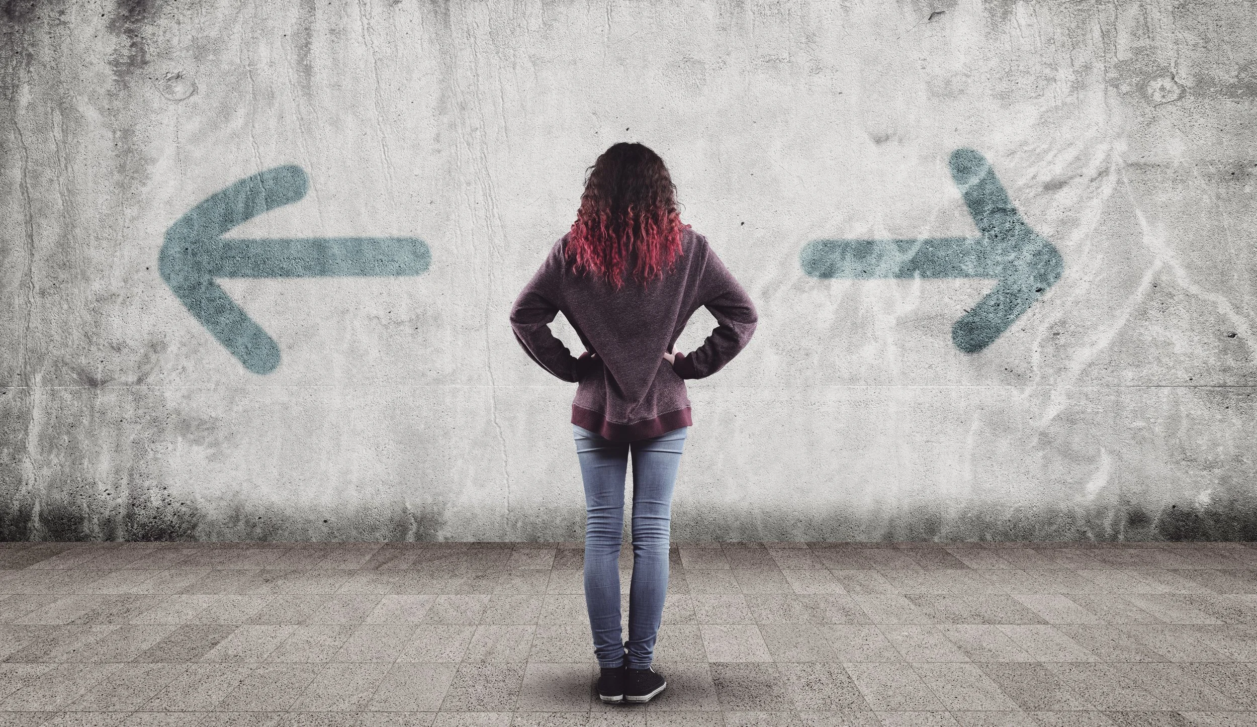 Woman contemplating a wall with arrows pointing in opposite directions