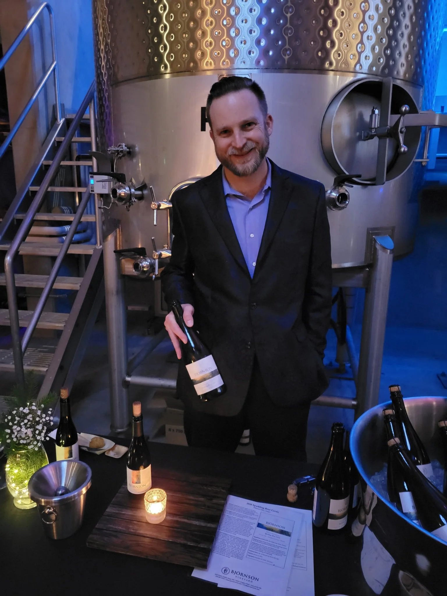 Scott holding bottle of wine at event