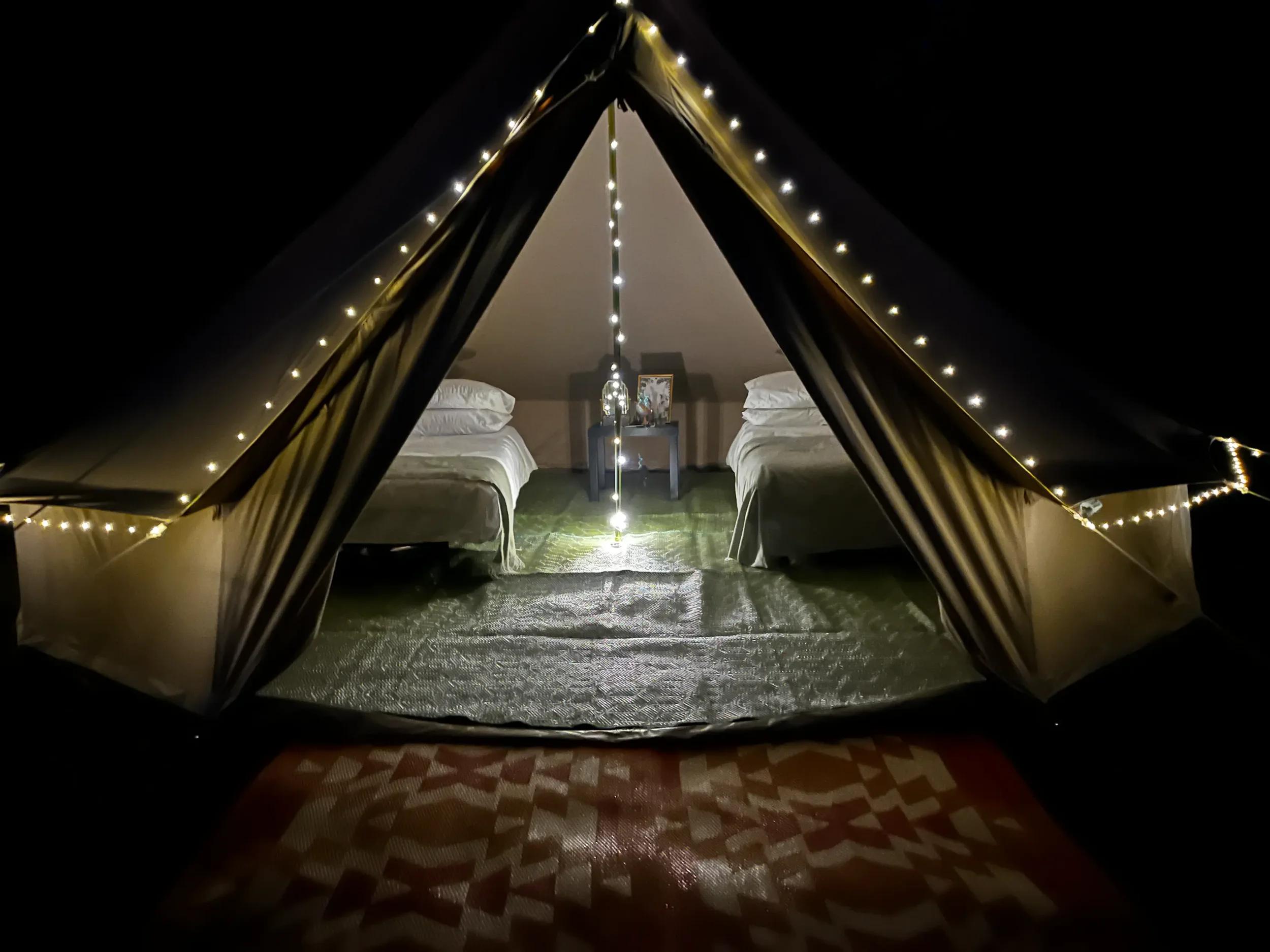 bell tent at night with fairylights outide and interior lighting inside luxury bell tent