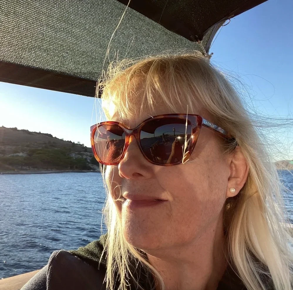woman with blonde hair wearing sunglasses on a boat out at sea
