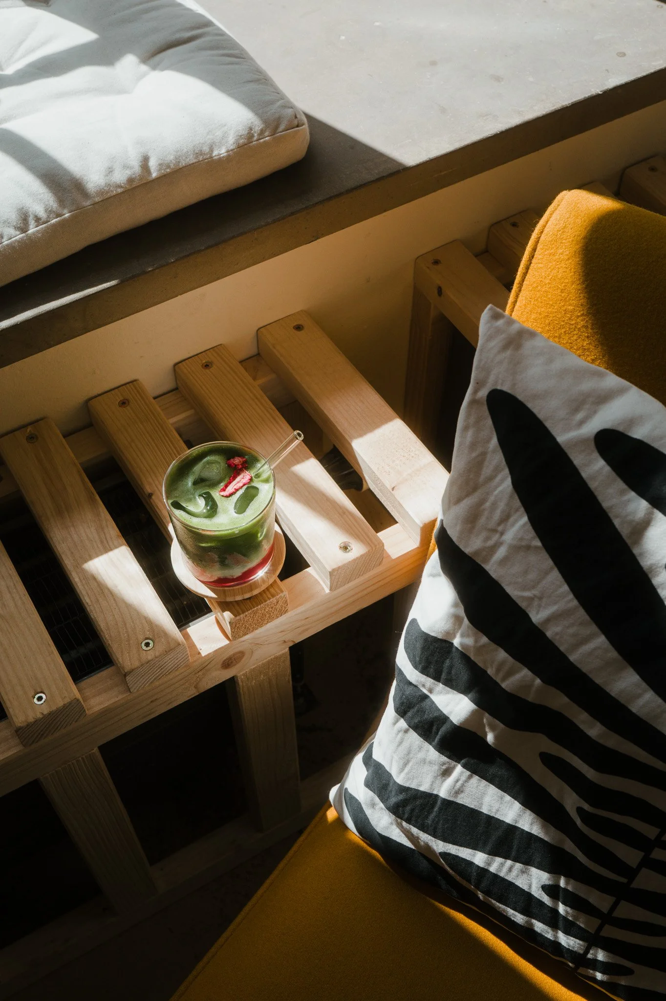 Ein grüner Cocktail mit Eiswürfeln und einer roten Dekoration auf einem Holzgestell