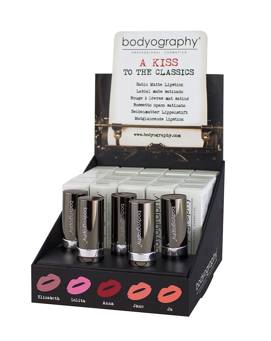 Display of Bodyography lipstick shades with a sign promoting the product, featuring different lip colors named Elizabeth, Lolita, Anna, Jane, and Jo.