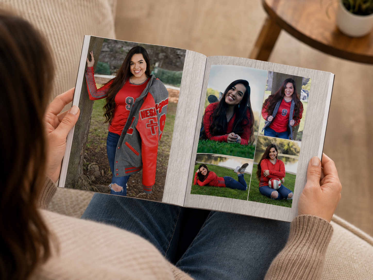 Person holding and looking at an open hardcover senior photo book featuring a collection of senior portraits.