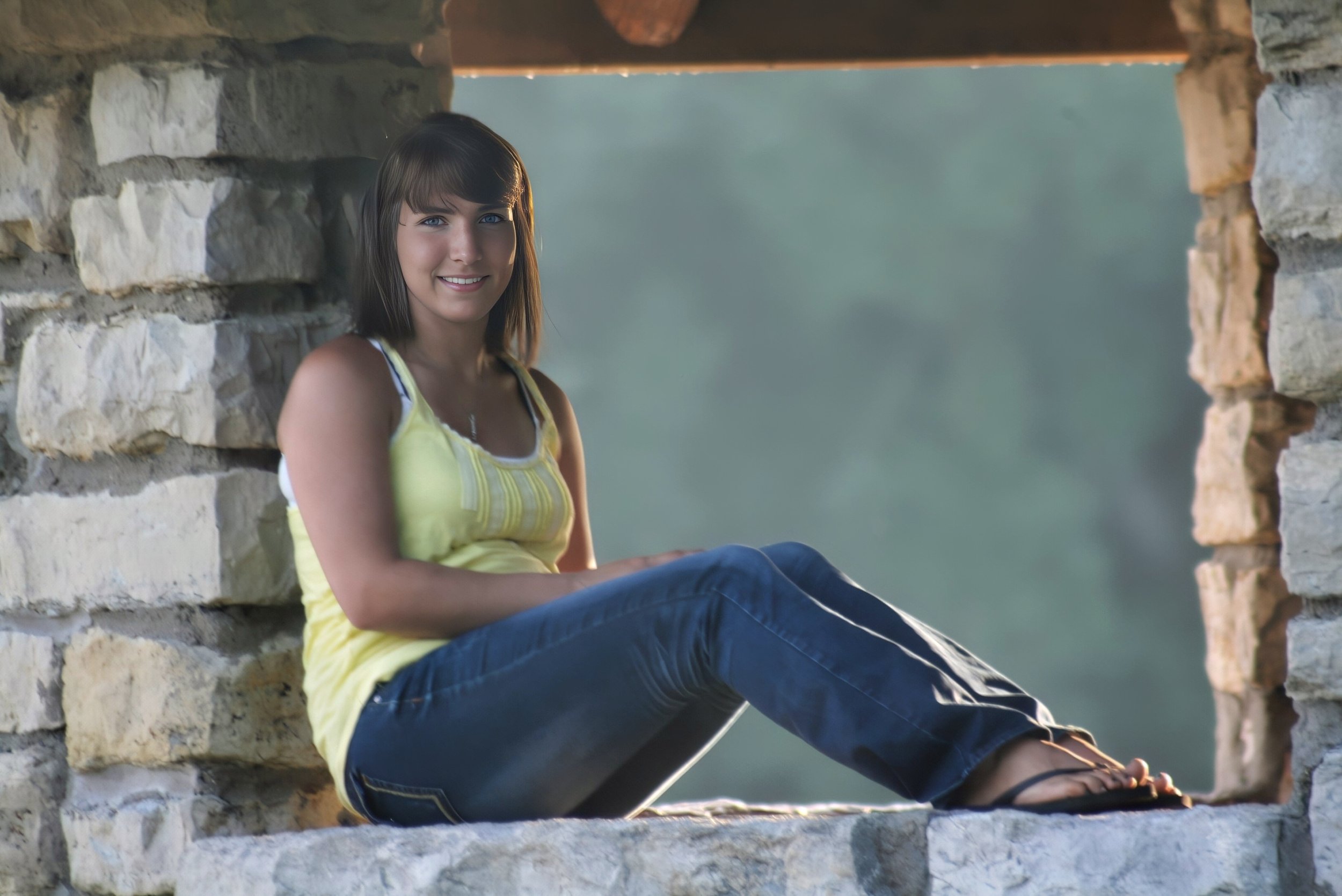 High school senior portrait of a girl framed in a stone window during her senior year.