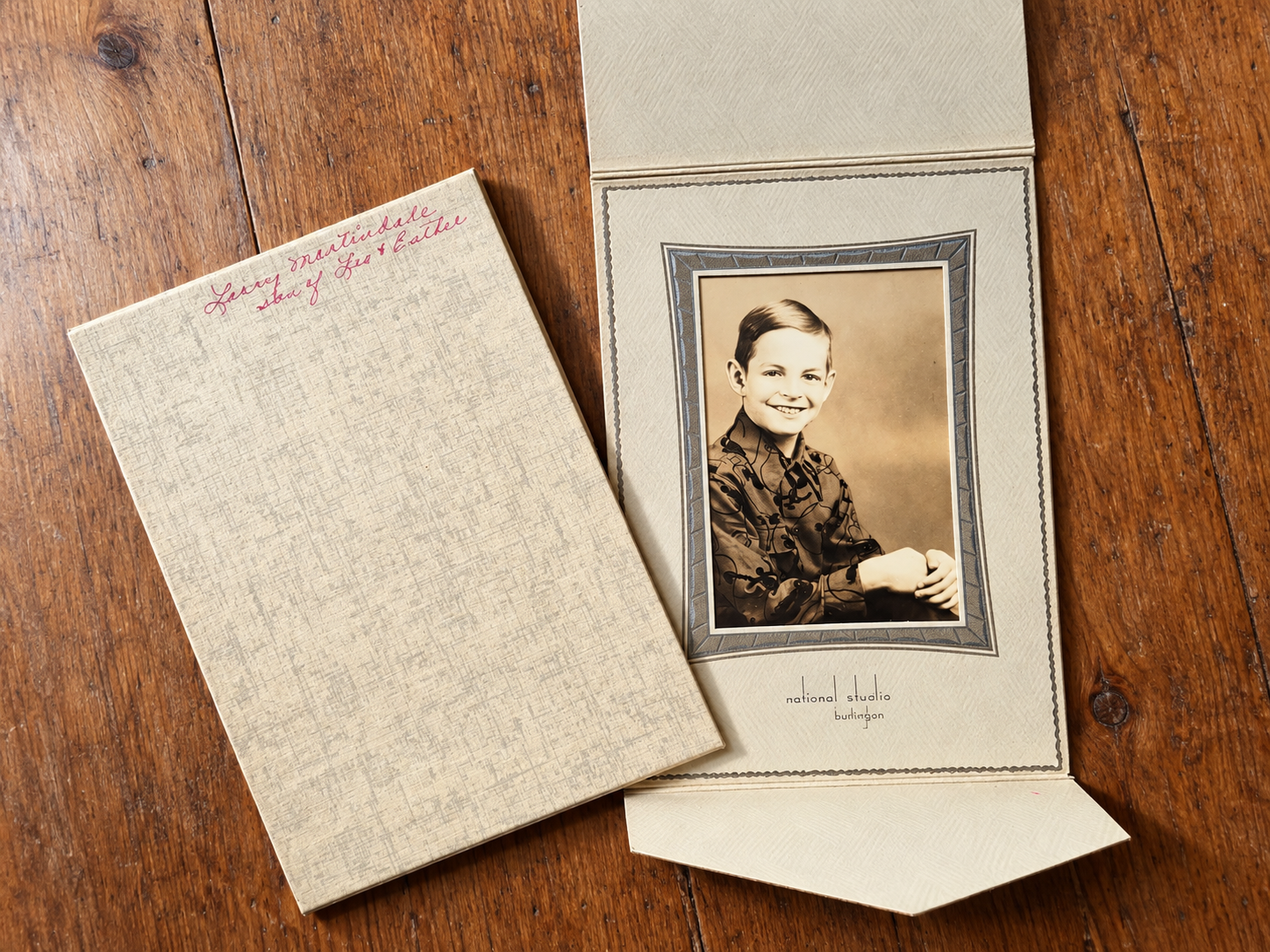 An old portrait in its original folder with handwritten identification on the outside, placed on a wooden table.