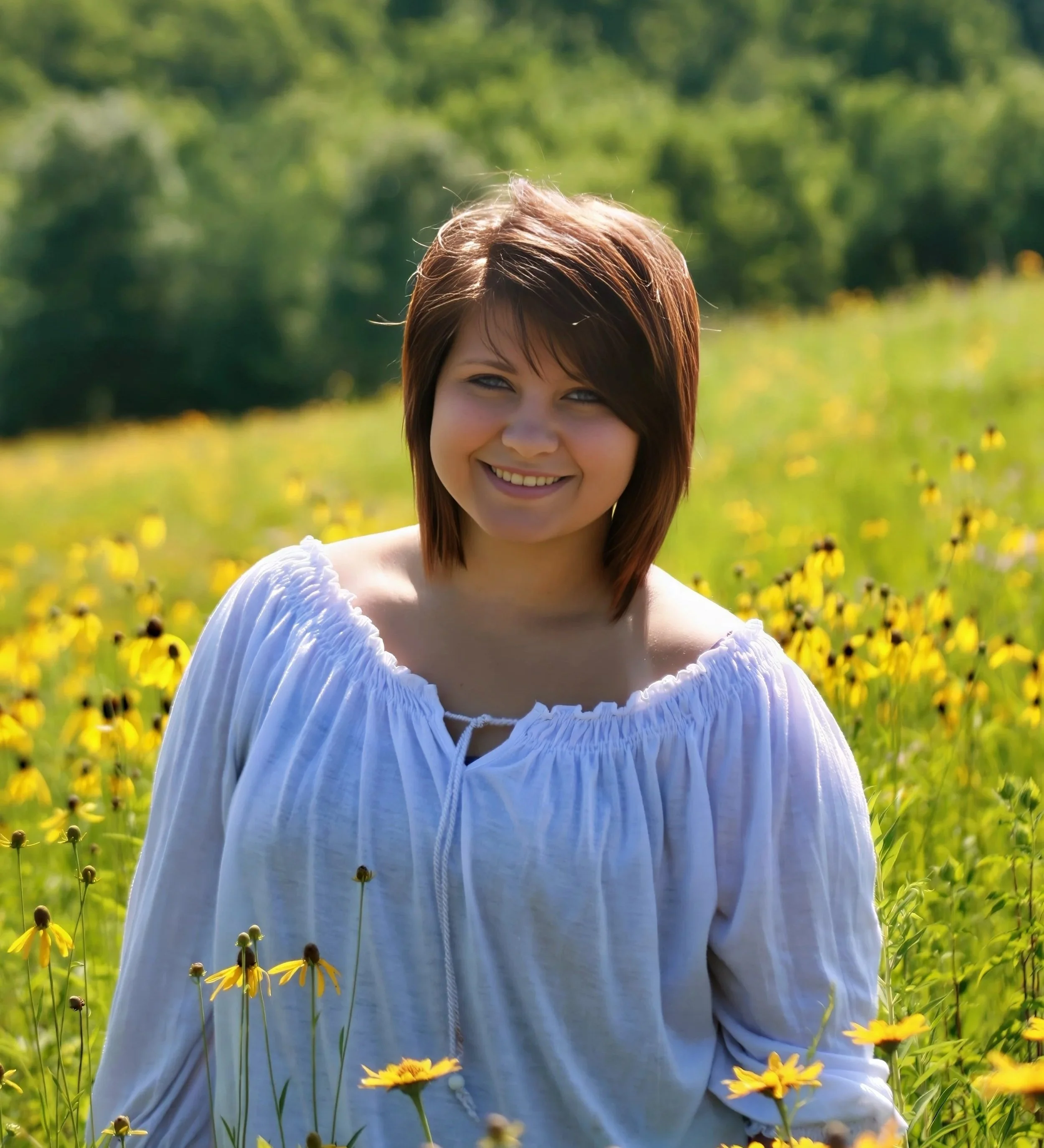 High school senior portrait of a girl standing in a field of yellow wildflowers during golden hour.