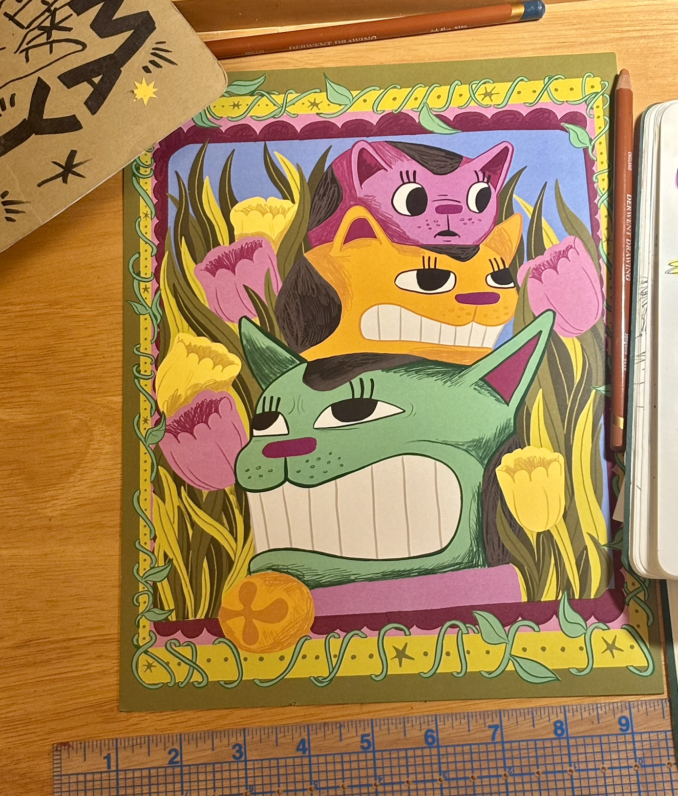 Colorful drawing of three cats with unique facial expressions, surrounded by tulips and greenery, bordered with a decorative vine. The cats are layered with the green one in front, the orange in the middle, and the purple behind.