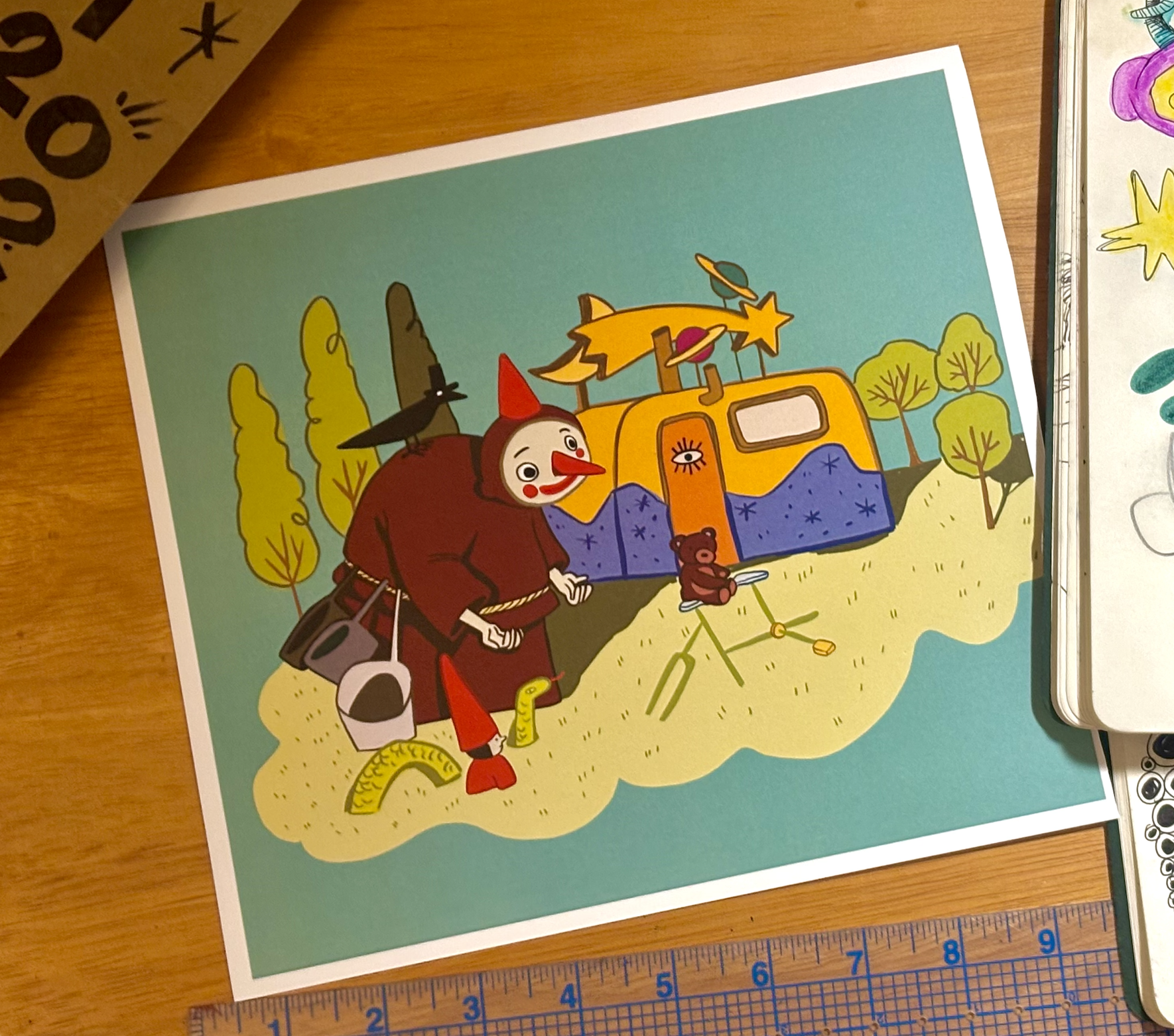 Colorful cartoon illustration of a whimsical scene with a clown, trees, a tent with eye details, a teddy bear on a bike, and various fantastical elements on a sandy hill